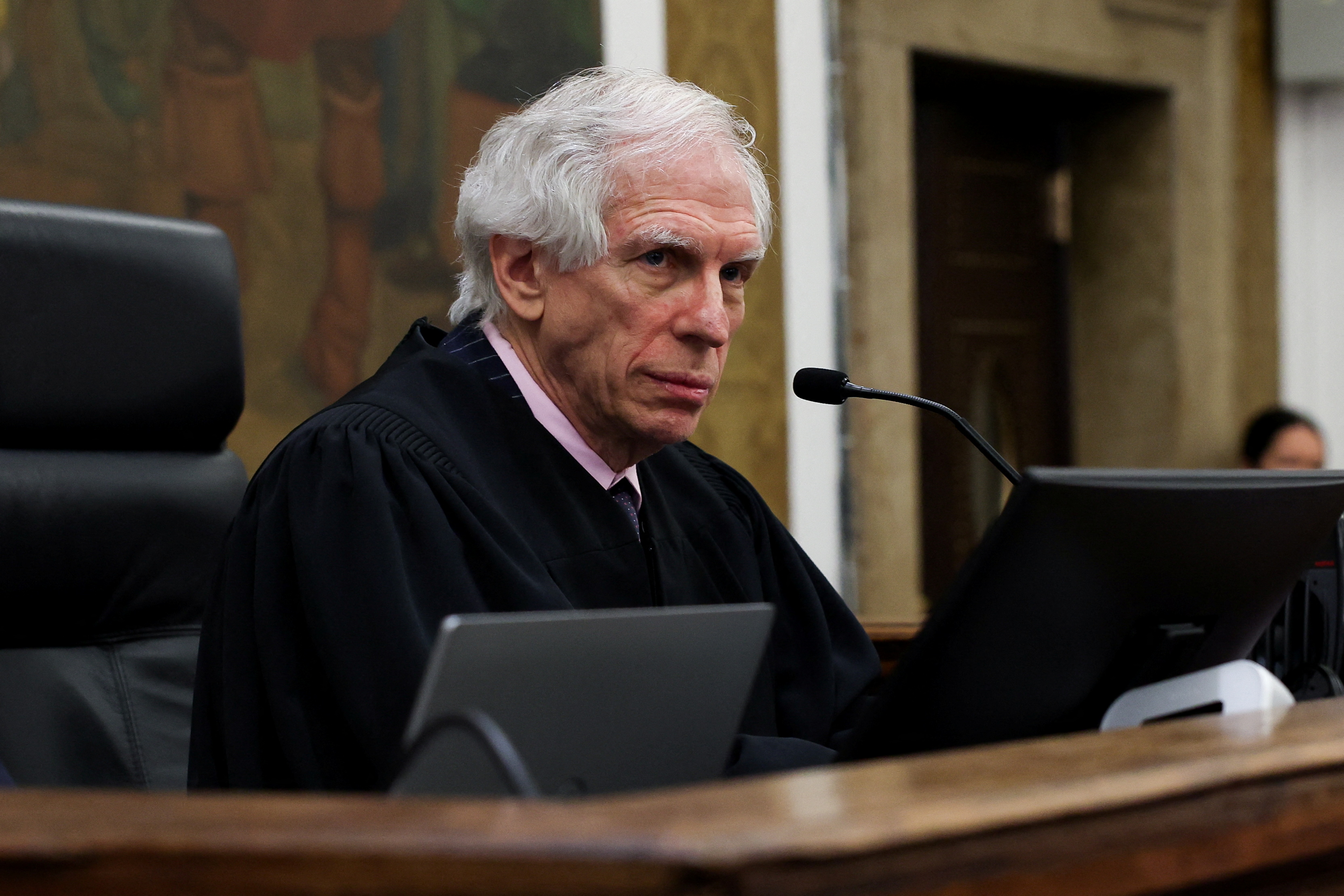 Judge Engoron sits behind a microphone and screen at his bench in court.