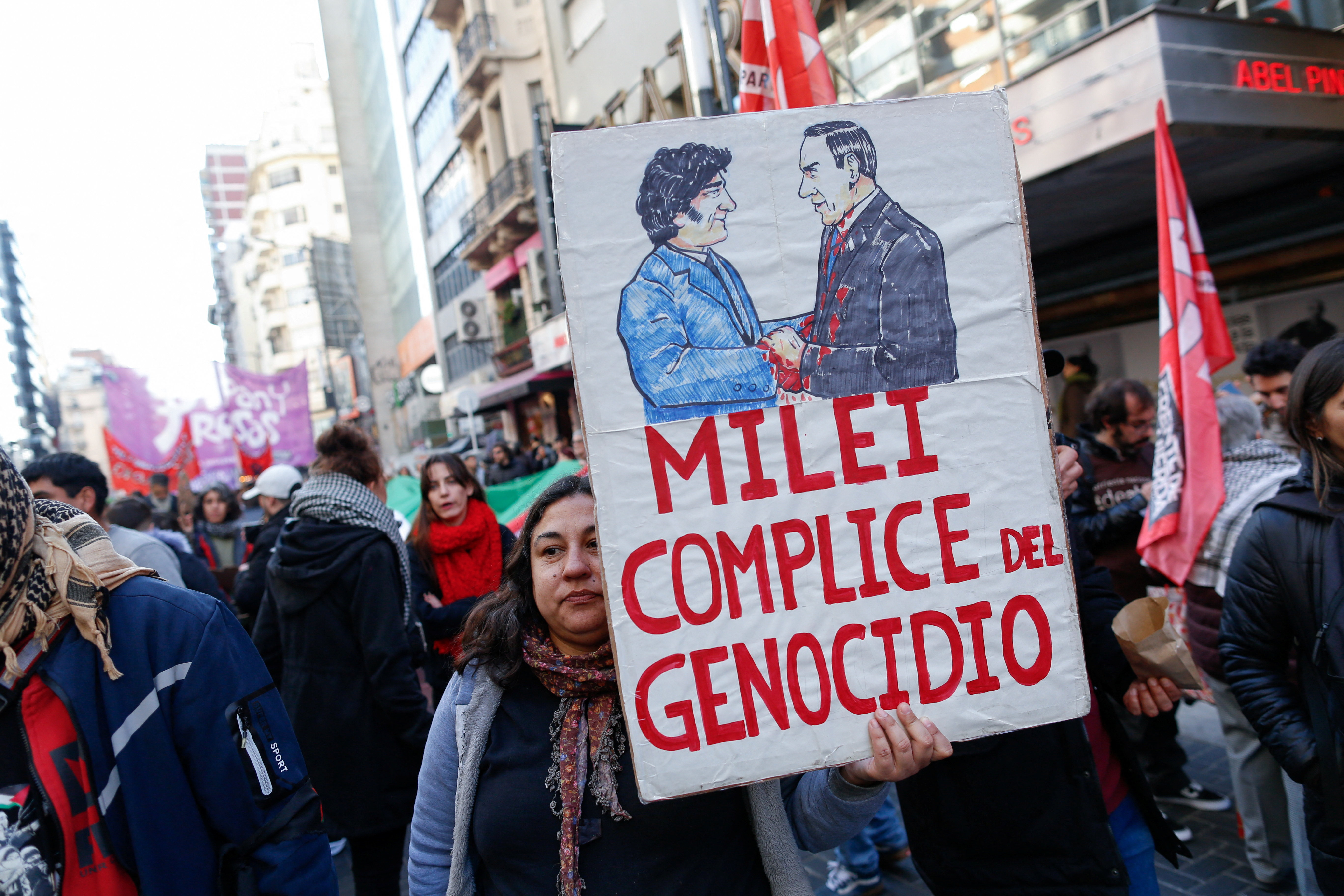 Protesters hold up a sign that reads, "Milei Complice en Genocidio"