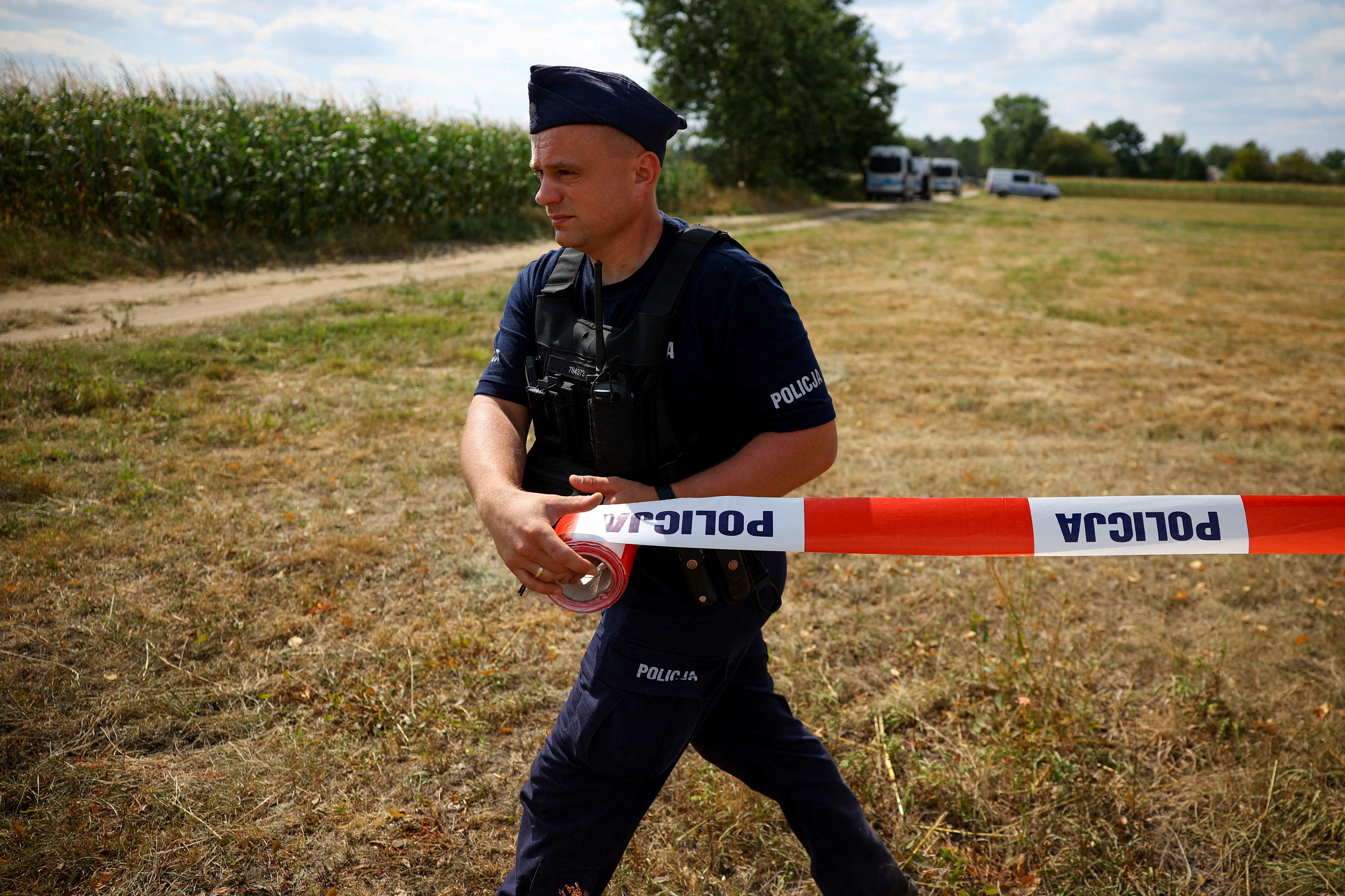 a police officer pulls police tape in front of a field