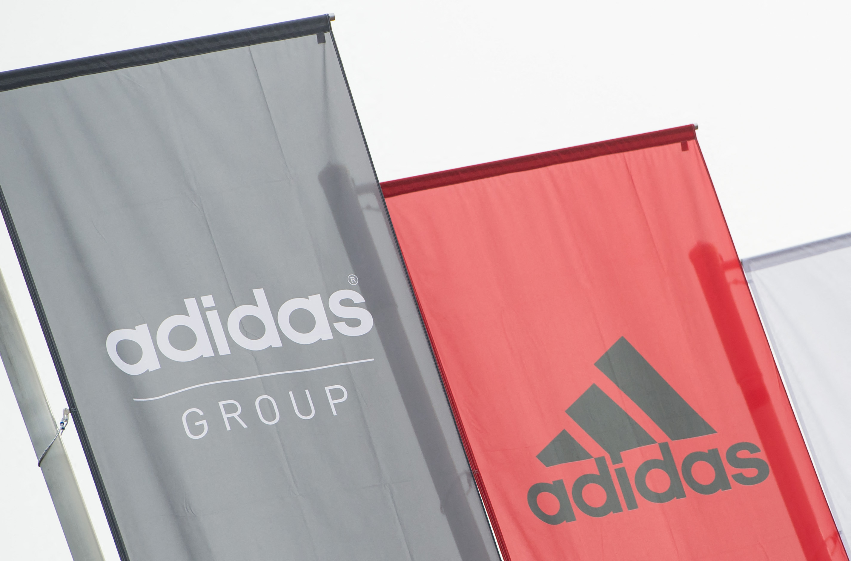 The logo of German sport brand Adidas is pictured on waving flags in front of the Adidas Headquarter in Herzogenaurach on January 25, 2016. (Photo by LUKAS BARTH / AFP)
