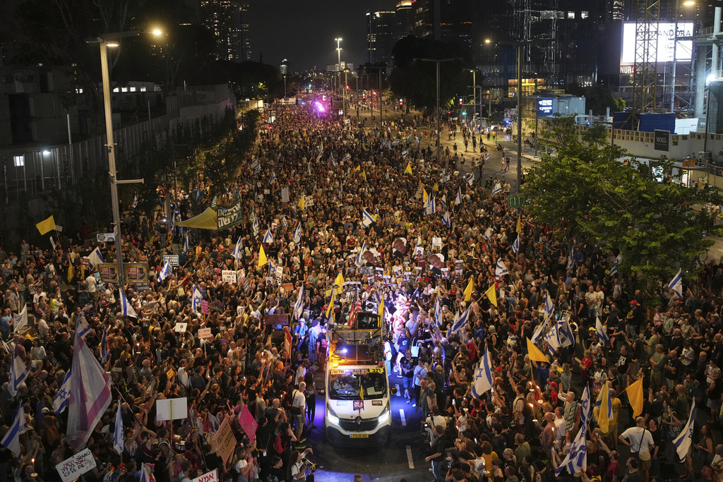 a large crowd of people walk in a street at night