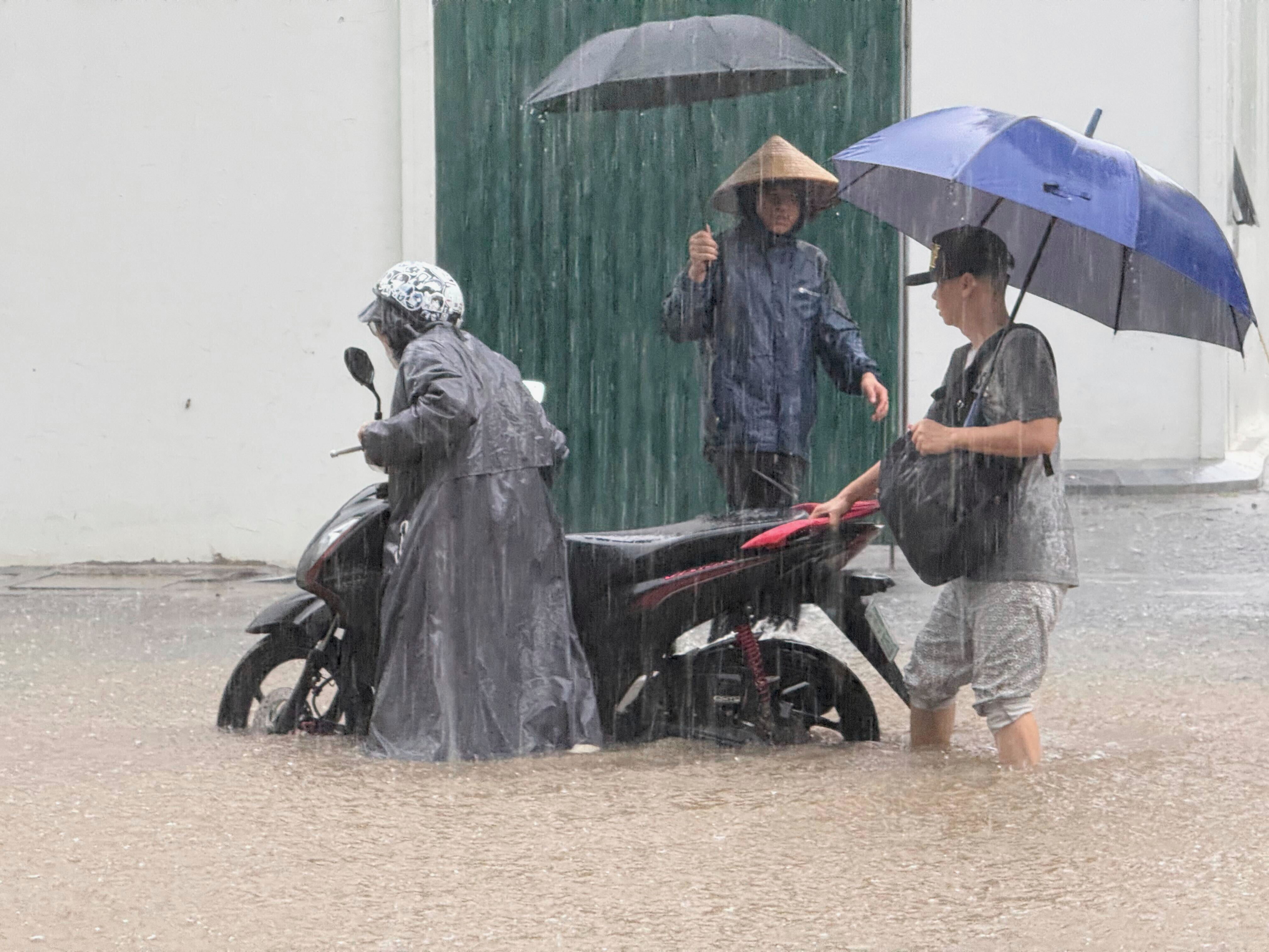 People push a motorbike through floods from heavy rains.
