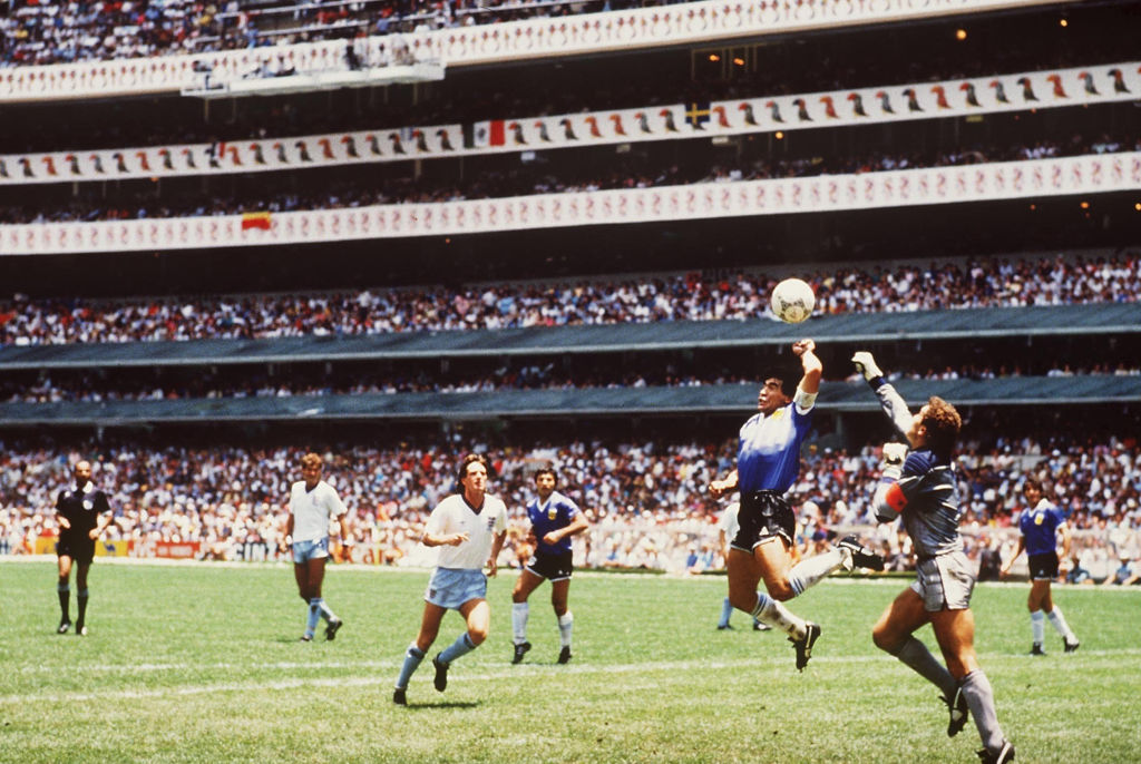 Diego Maradona of Argentina handles the ball past Peter Shilton of England to score the opening goal of the World Cup Quarter Final