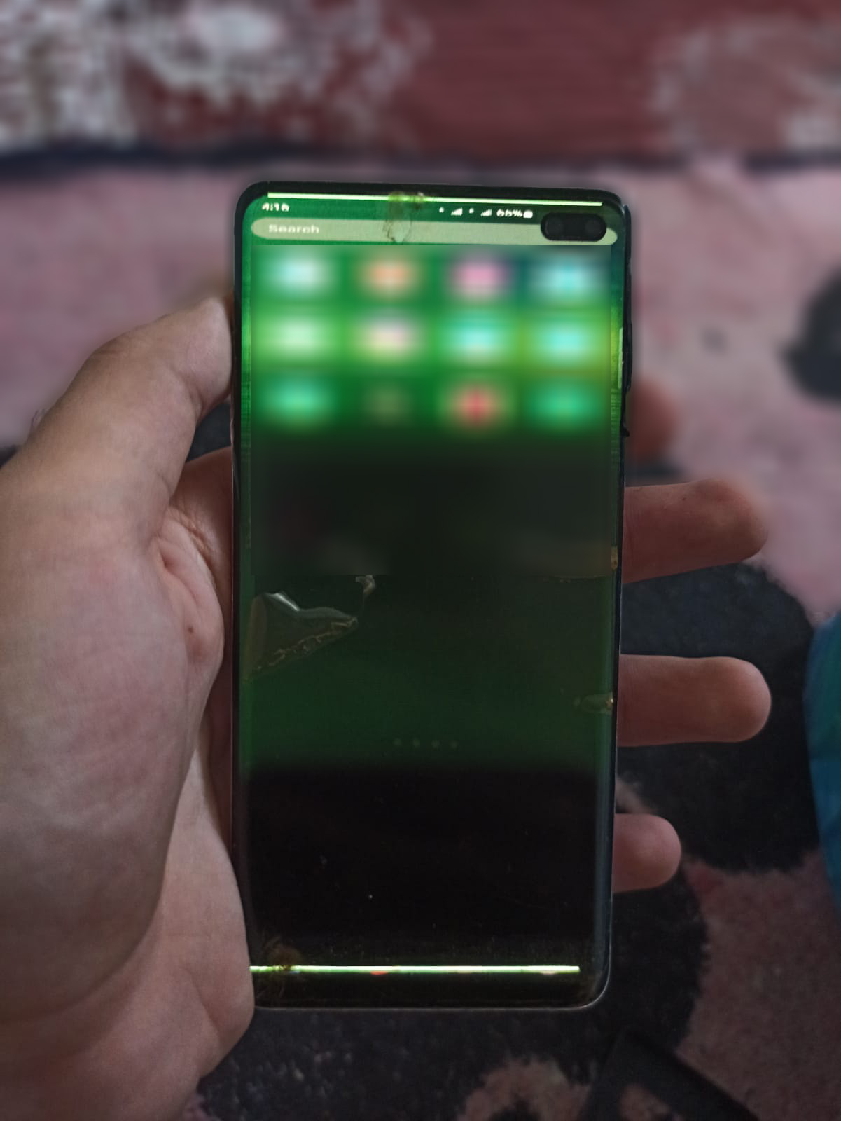The writer's hand holding his glitching phone, with an illegibly fuzzy screen.