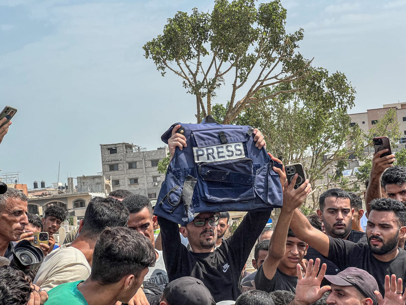 A man in Gaza holds of the press vest of slain Al Jazeera journalist Anas al-Sharif after he was buried along with four of his colleagues. Al-Sharif was killed in a targeted strike by Israel