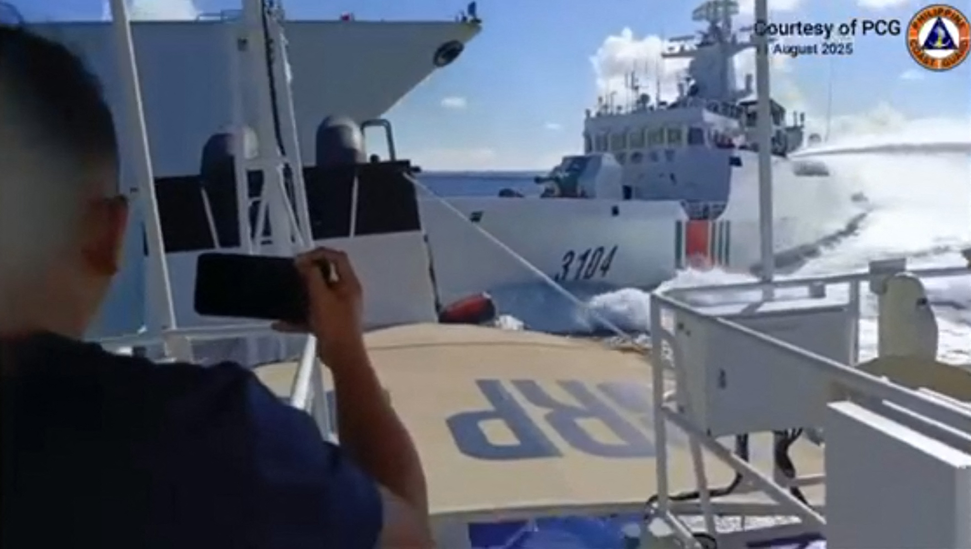 This handout video grab released and taken on August 11, 2025 by the Philippine Coast Guard shows an incident between a Chinese Navy vessel (L) and a Chinese Coast Guard ship (R) as seen from a Philippine fisheries boat near Scarborough Shoal in the disputed South China Sea.