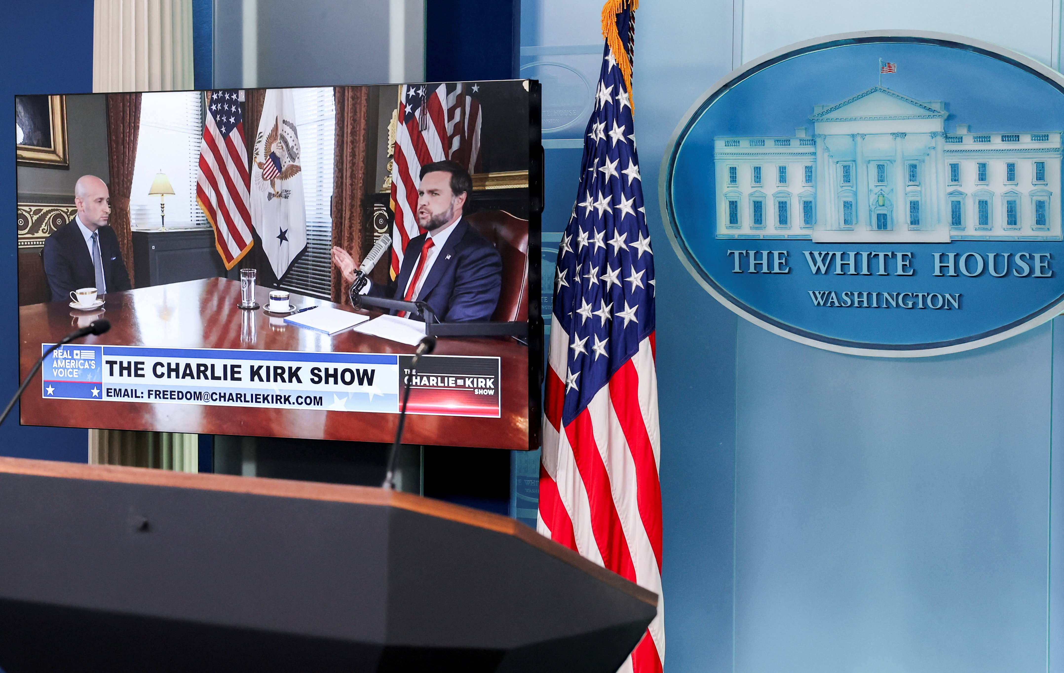 US Vice President JD Vance and White House Deputy Chief of Staff Stephen Miller appear on video monitors in the press briefing room as guest presenters for the podcast of murdered right-wing influencer Charlie Kirk at the White House in Washington, DC, September 15, 2025. [Jonathan Ernst/Reuters]