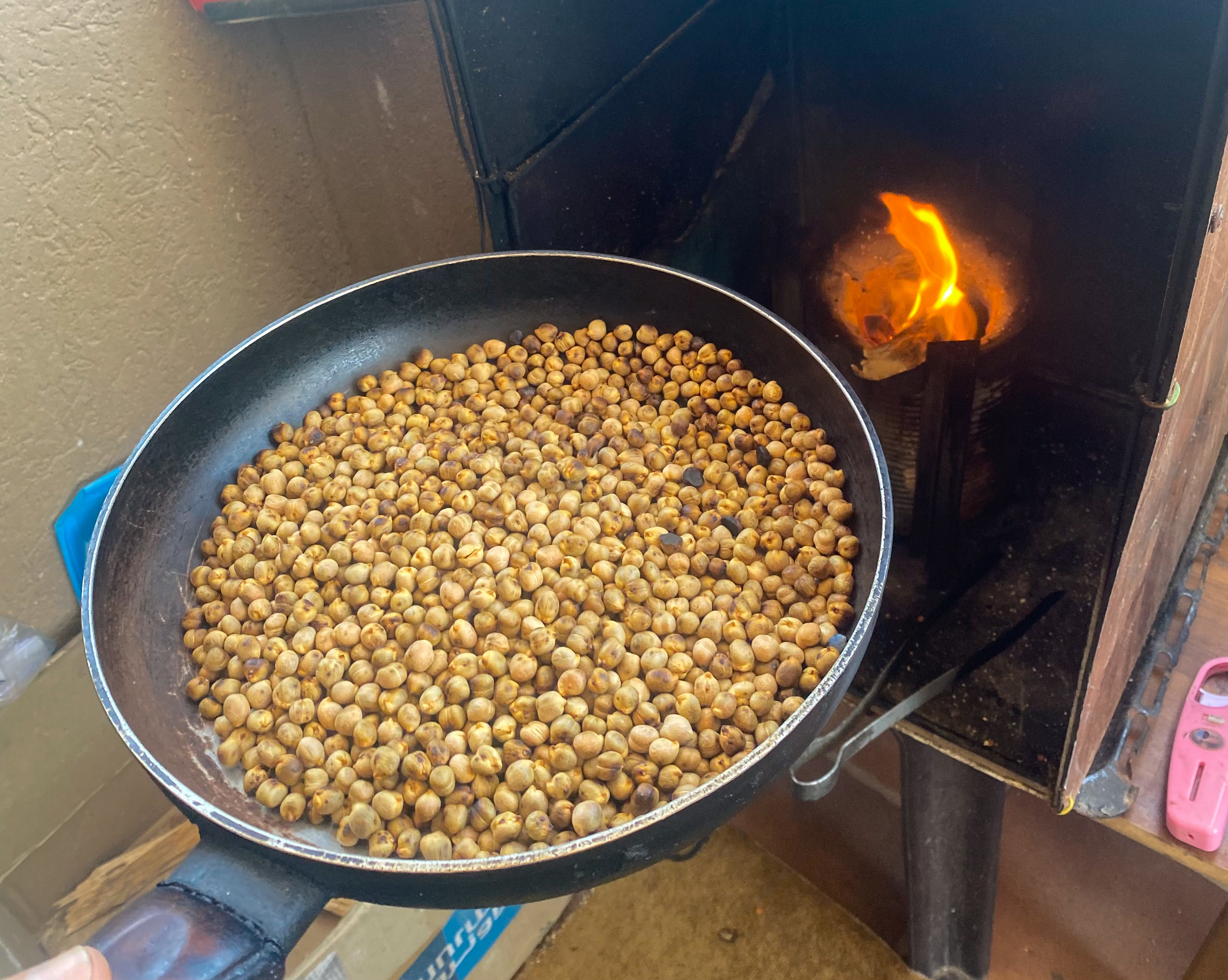 A pan of chickpeas going into an open-flame oven to be roasted