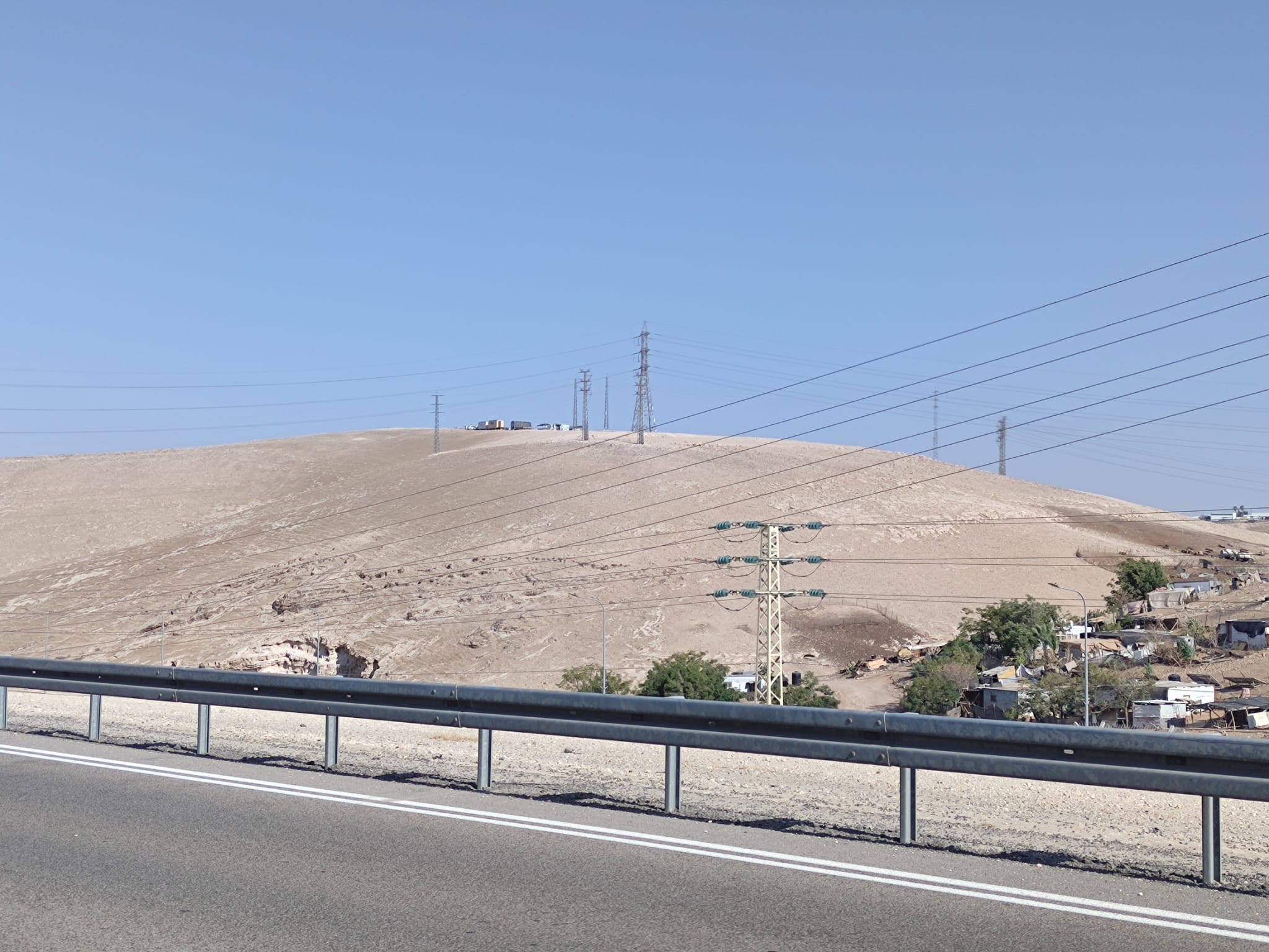 Small buildings in the distant on top of a hill next to a road