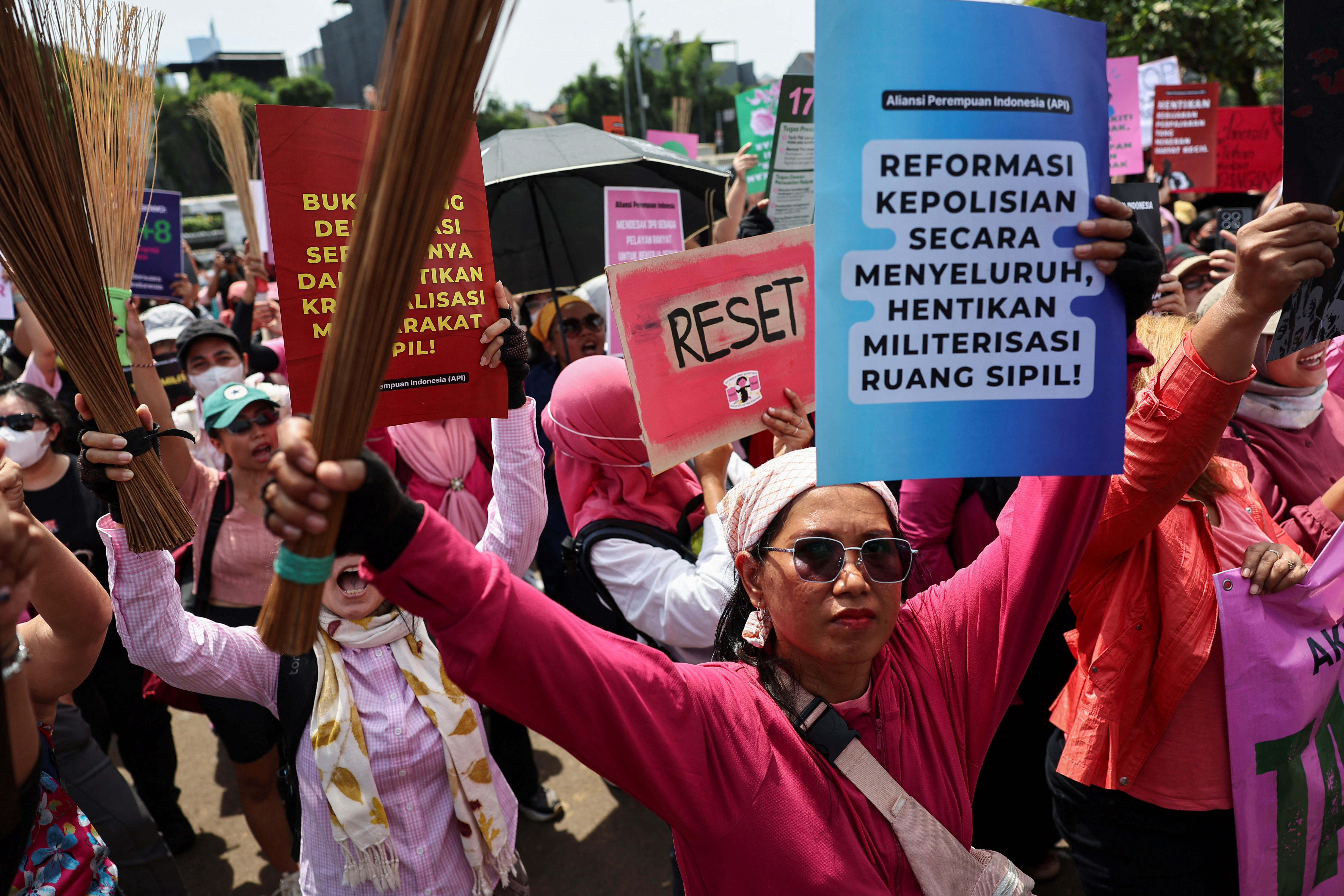 Women holding up brooms and placards attend a protest against lawmakers' perks and police brutality, brandishing brooms as a symbol of their calls for reform, outside the Indonesian parliament building in Jakarta, Indonesia, September 3, 2025. REUTERS/Willy Kurniawan