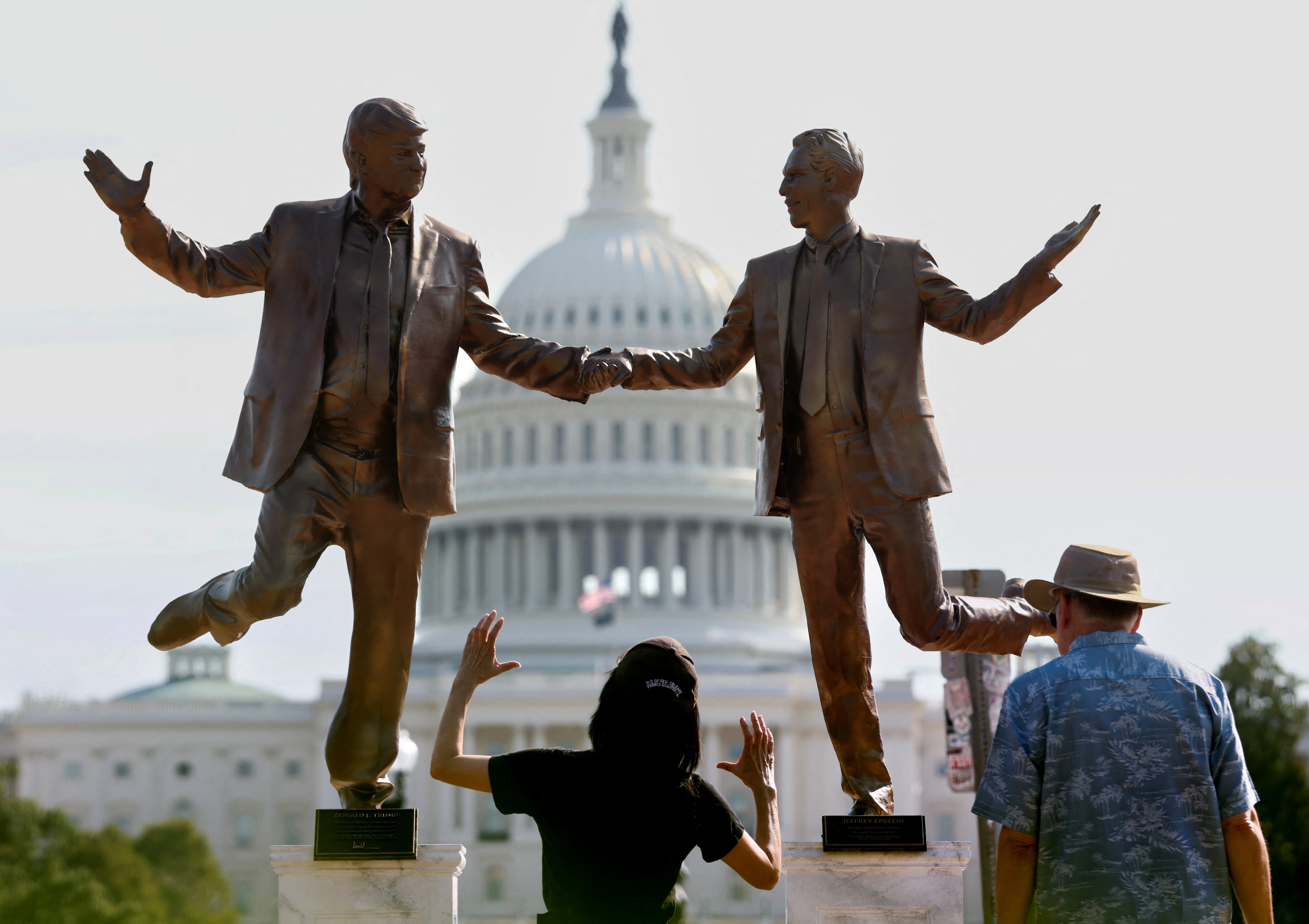 Visitors look up at a pop-up statue depicting U.S. President Donald Trump and disgraced financier and sex offender Jeffrey Epstein dancing together near the U.S. Capitol in Washington, D.C., U.S., September 23, 2025. REUTERS/Kevin Lamarque