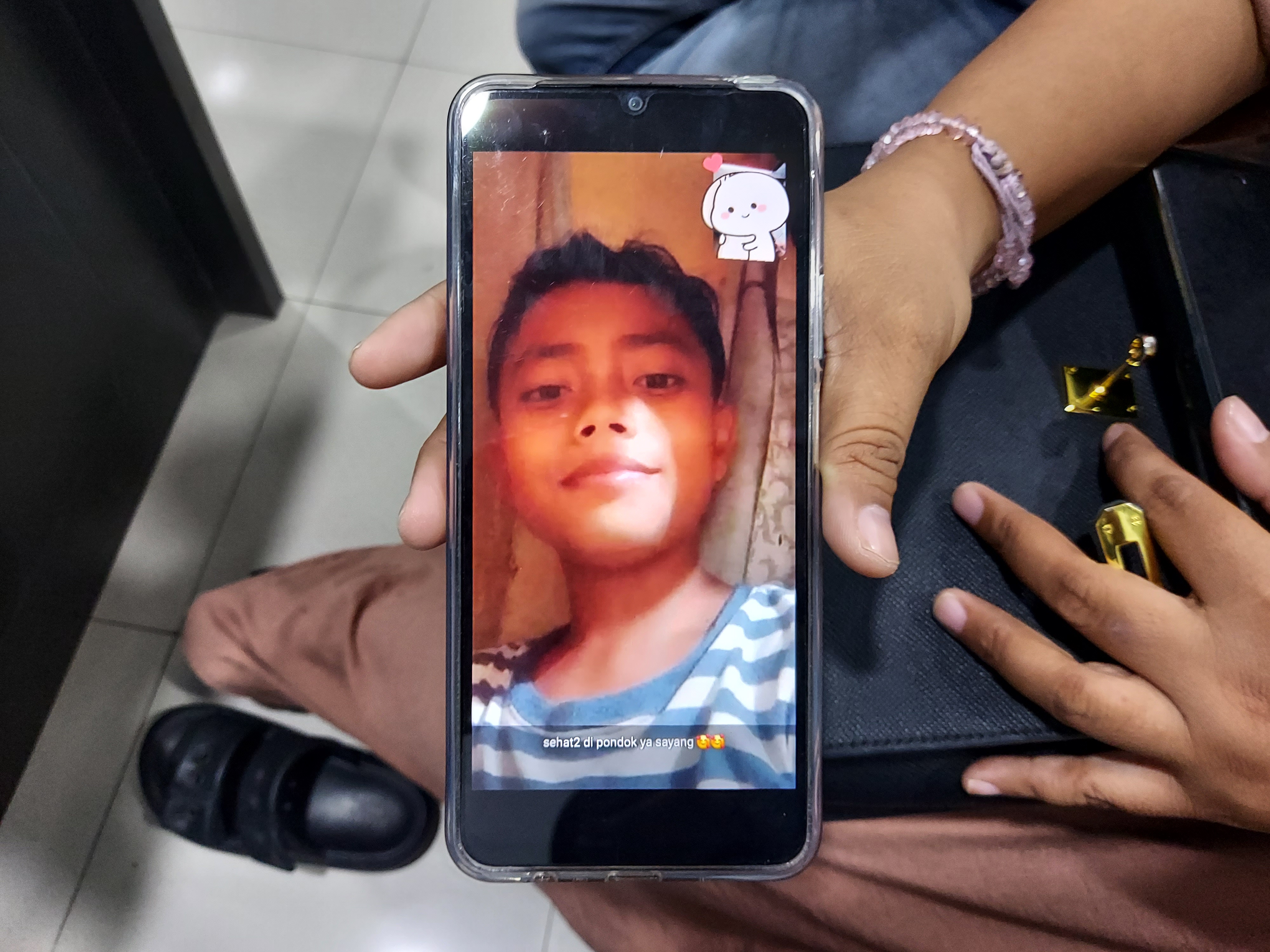 Dewi Ajeng shows a screenshot image of son, Haikal, taken during a video chat a few hours before his school collapsed and he was trapped beneath its rubble, in Sidoarjo, East Java, Indonesia [Aisyah Llewellyn/Al Jazeera]