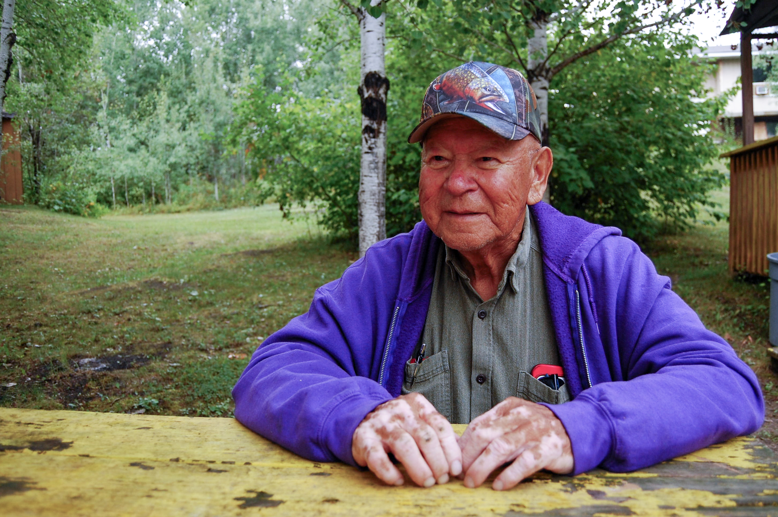 William 'Bill' Fobister, 79, sits at a picnic table in his backyard