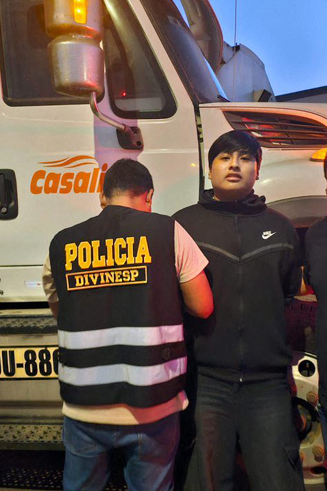This handout picture released by Peru's National Police shows Peruvian police officers arresting "Pequeño J" (C) in Pucusana, Peru on September 30, 2025. Considered the mastermind behind a brutal triple murder of women that authorities suspect is linked to drug trafficking in Argentina.