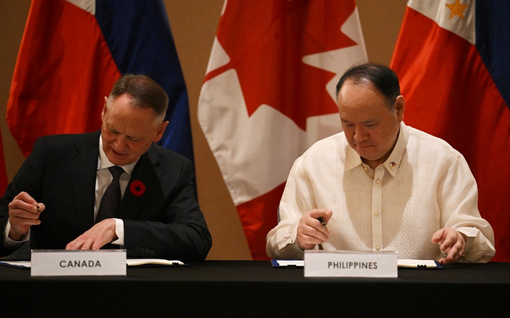 Philippines' Secretary of National Defence Gilberto Teodoro (R) and Canadian Minister of Defence David McGuinty sign documents of the visiting forces agreement after their bilateral meeting in Manila on November 2, 2025. [Ted Aljibe/AFP]