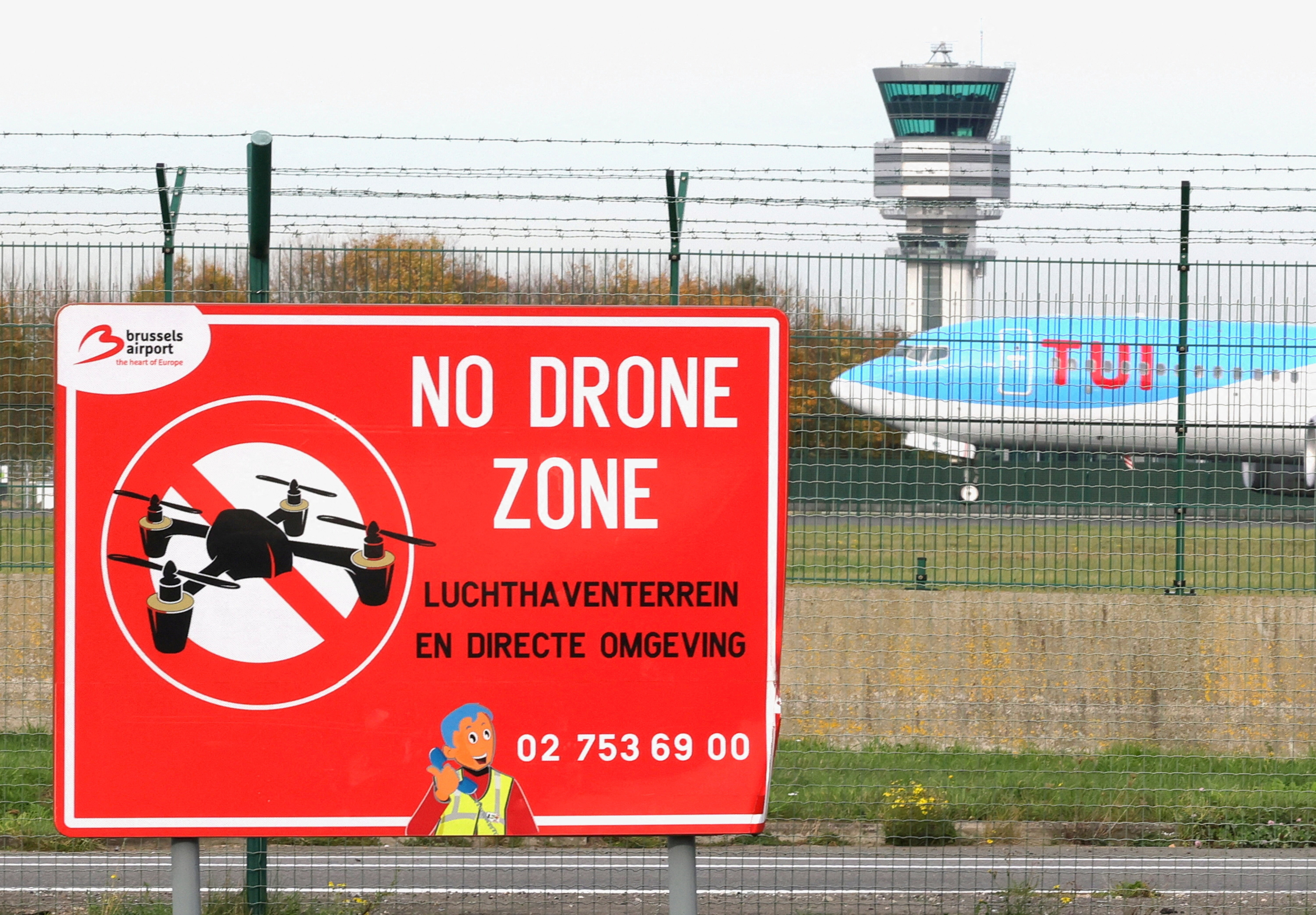 An aircraft lands on the tarmac at Brussels airport near to a "No Drone Zone" sign.