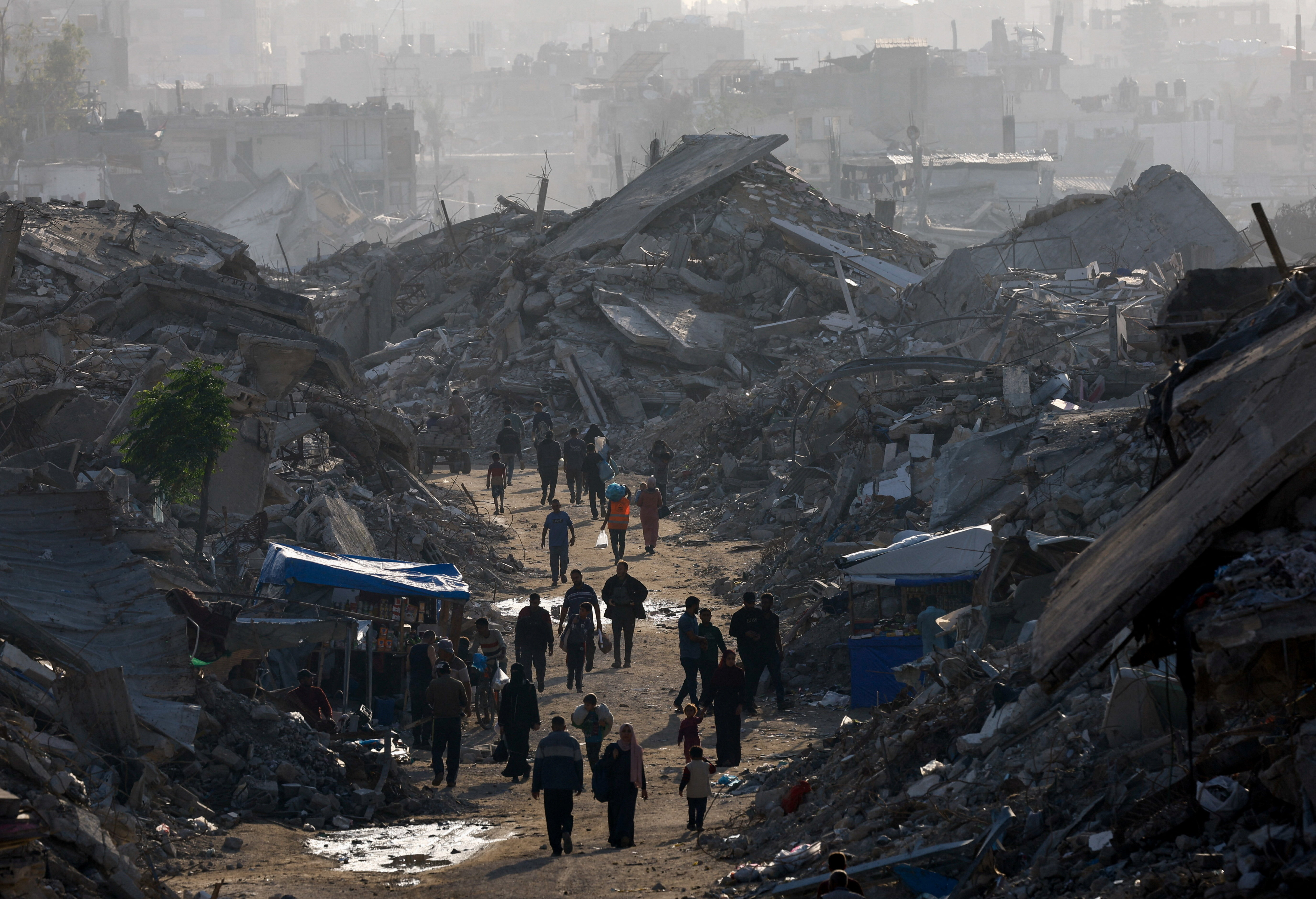 Palestinians walk among piles of rubble in the northern Gaza Strip November 19, 2025. [Mahmoud Issa/Reuters]