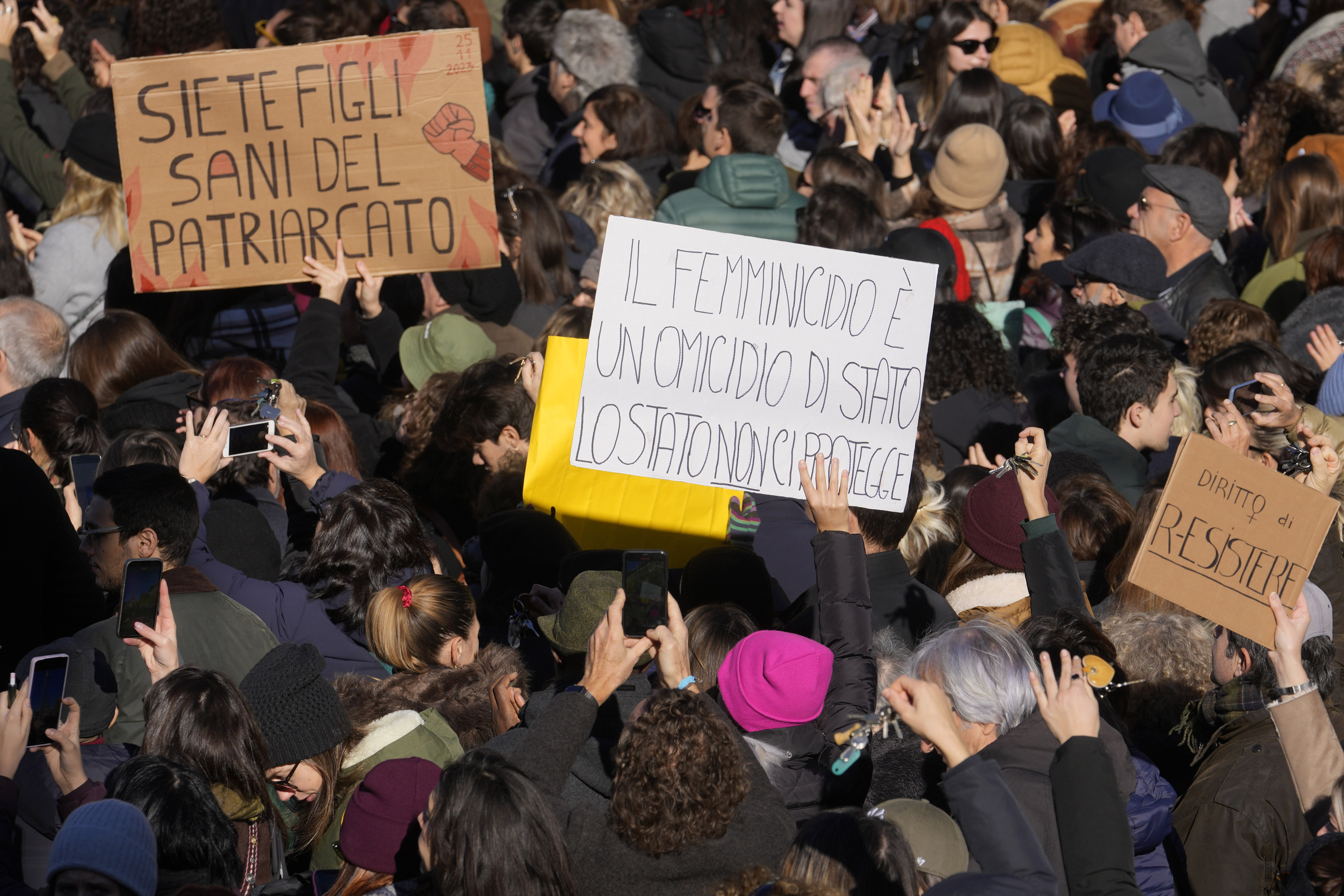 Women hold banners reading 'You are healthy children of patriarchy' and 'Femicide is a state murder, the state does not protect us' during a gathering for the International Day for the Elimination of Violence Against Women in Milan, Italy, on November 25, 2023 [Luca Bruno/AP Photo]