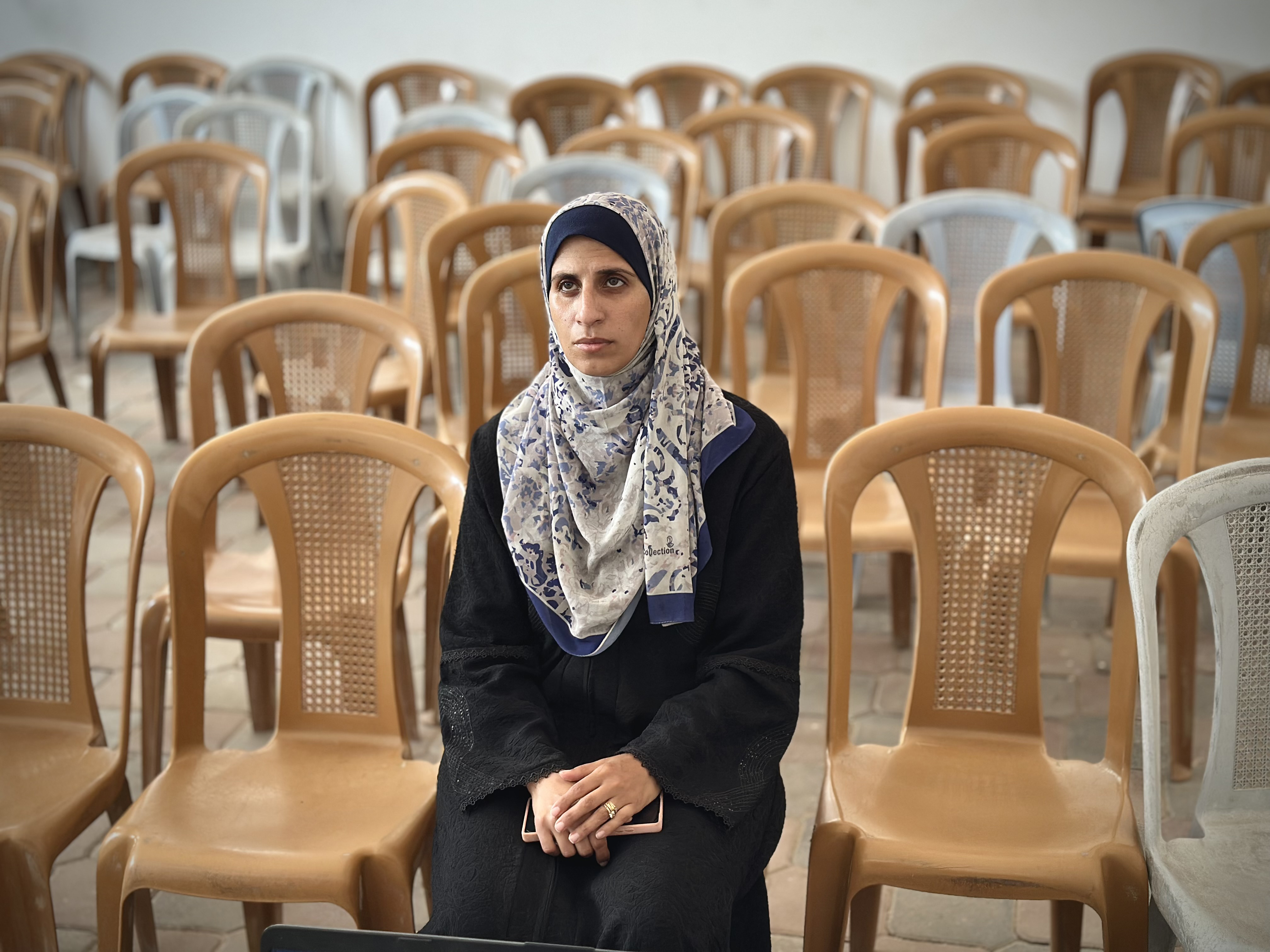 Israa al-Areer sits on a chair with empty chairs surrounding her