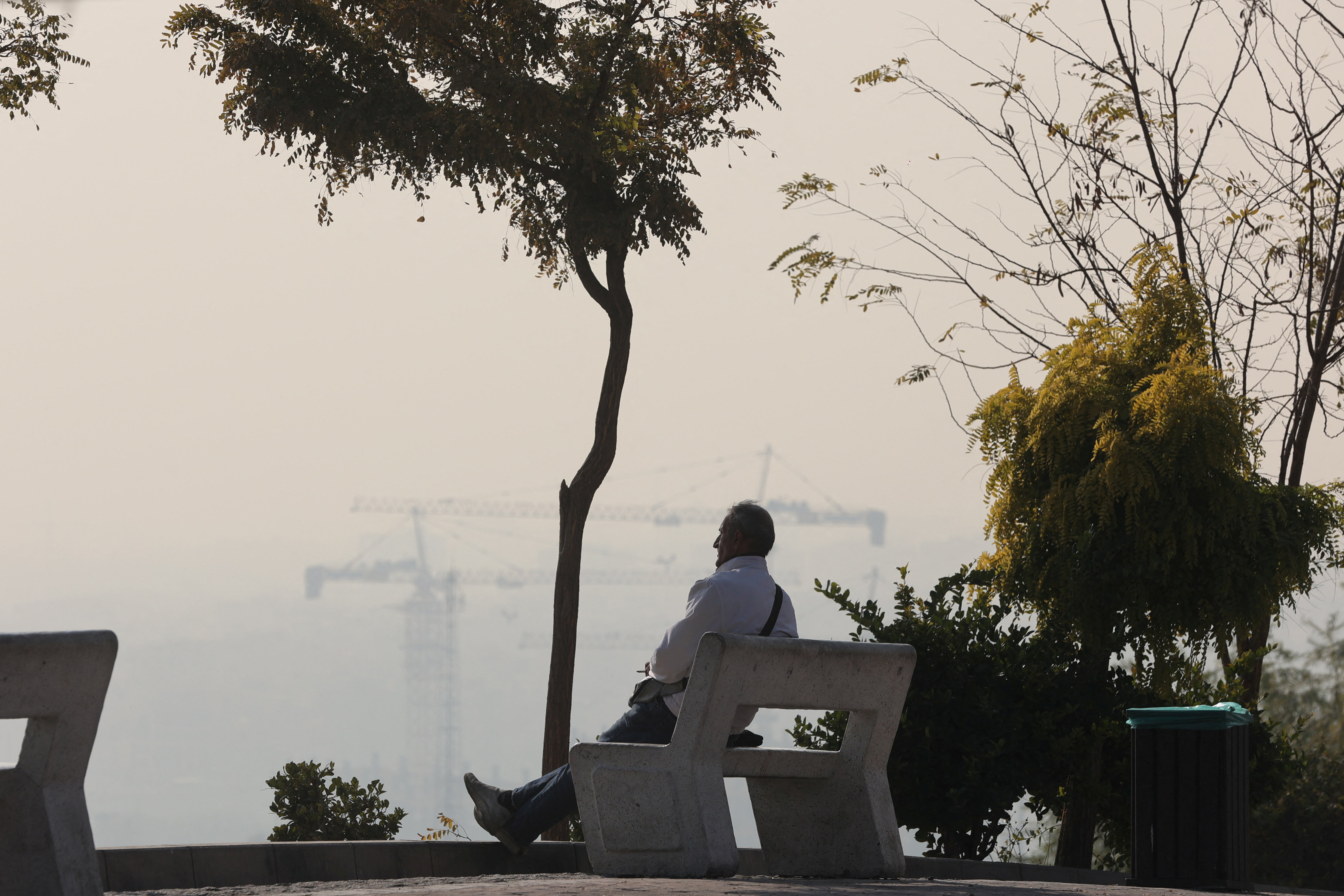 A man sits in a park, following the increase in air pollution in Tehran, Iran, November 22, 2025. Majid Asgaripour/WANA (West Asia News Agency) via REUTERS ATTENTION EDITORS - THIS PICTURE WAS PROVIDED BY A THIRD PARTY