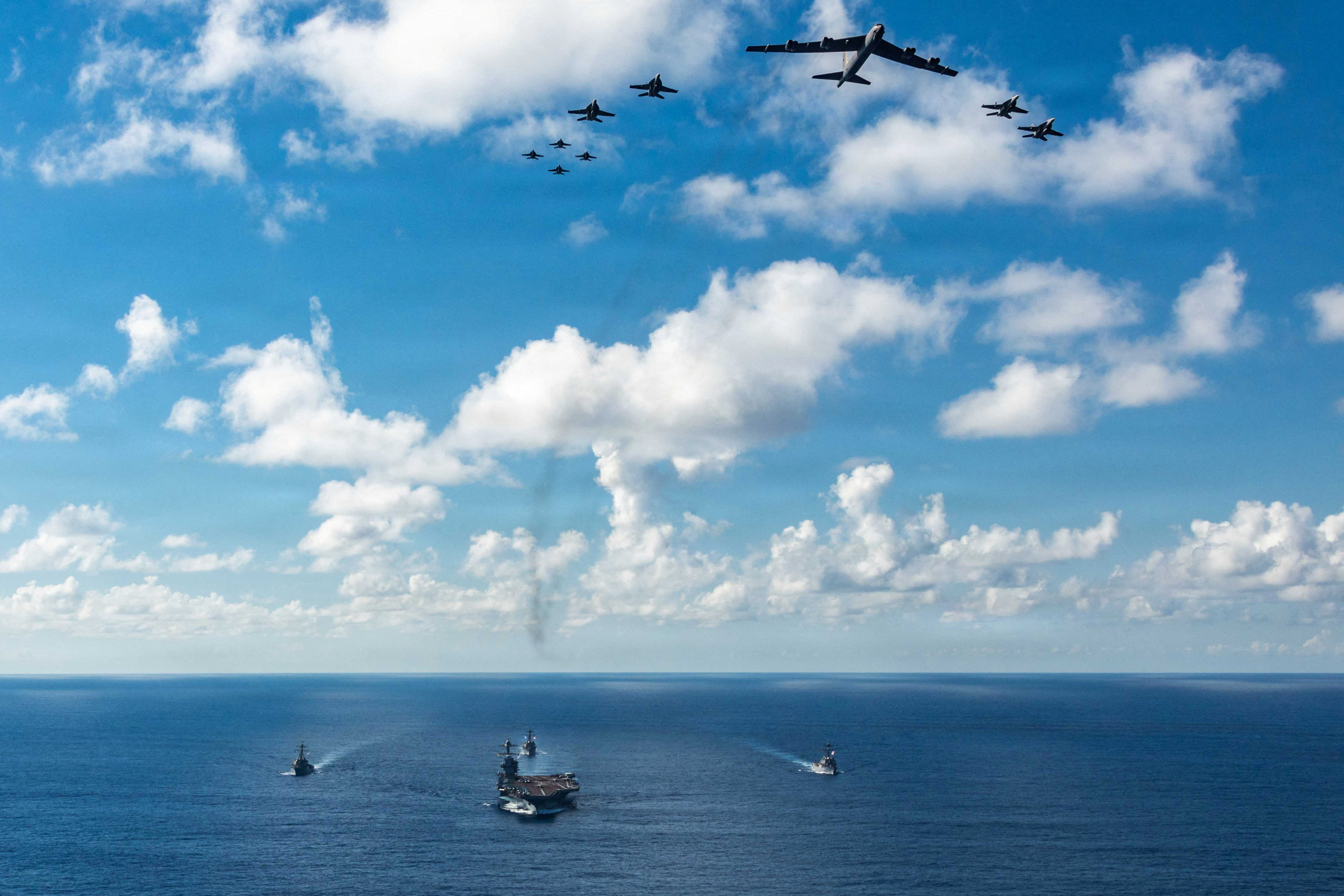A fleet of US warships sail in the sea.