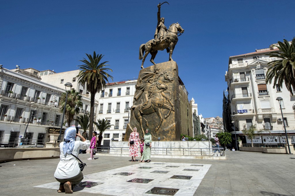 Women pose for a picture before the equestrian statue of Emir Abdelkader ibn Muhieddine
