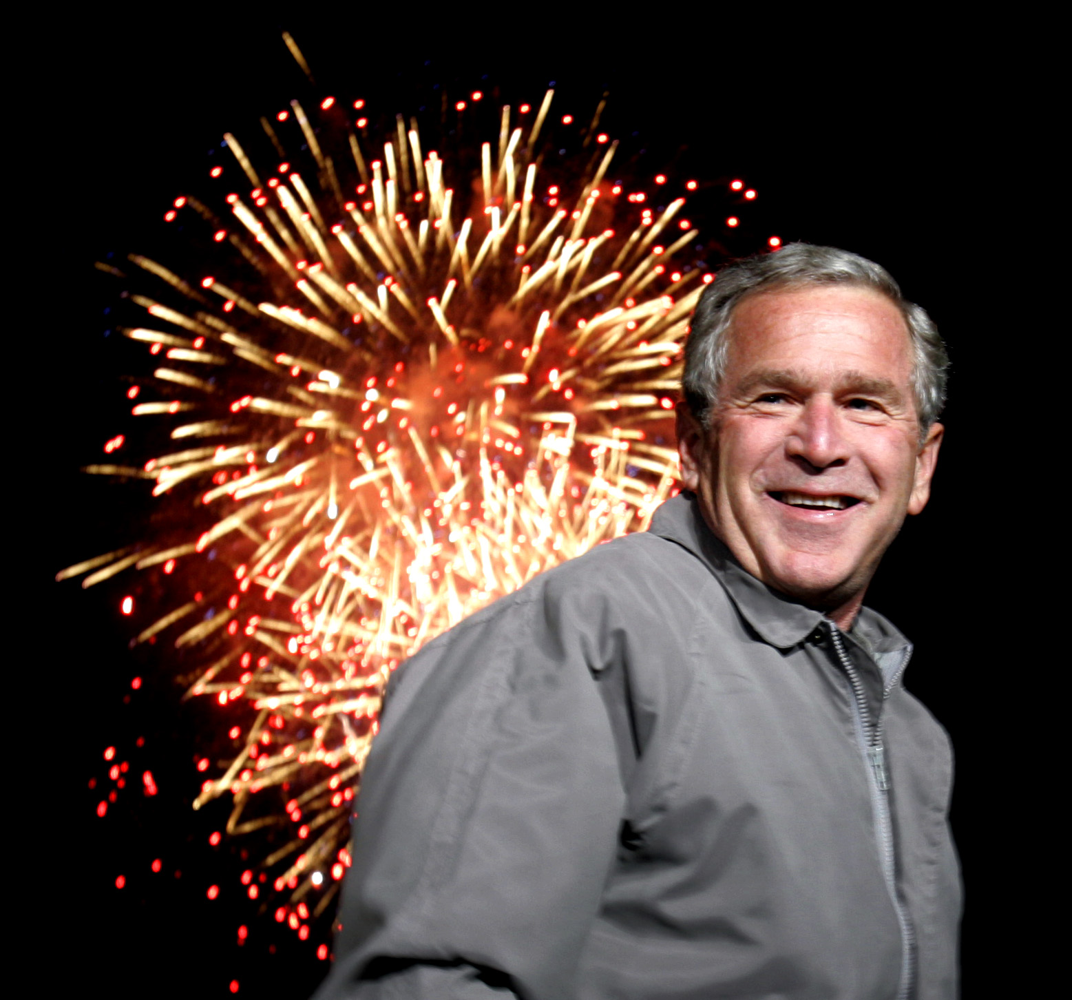 Fireworks light up the sky as US President George W Bush smiles