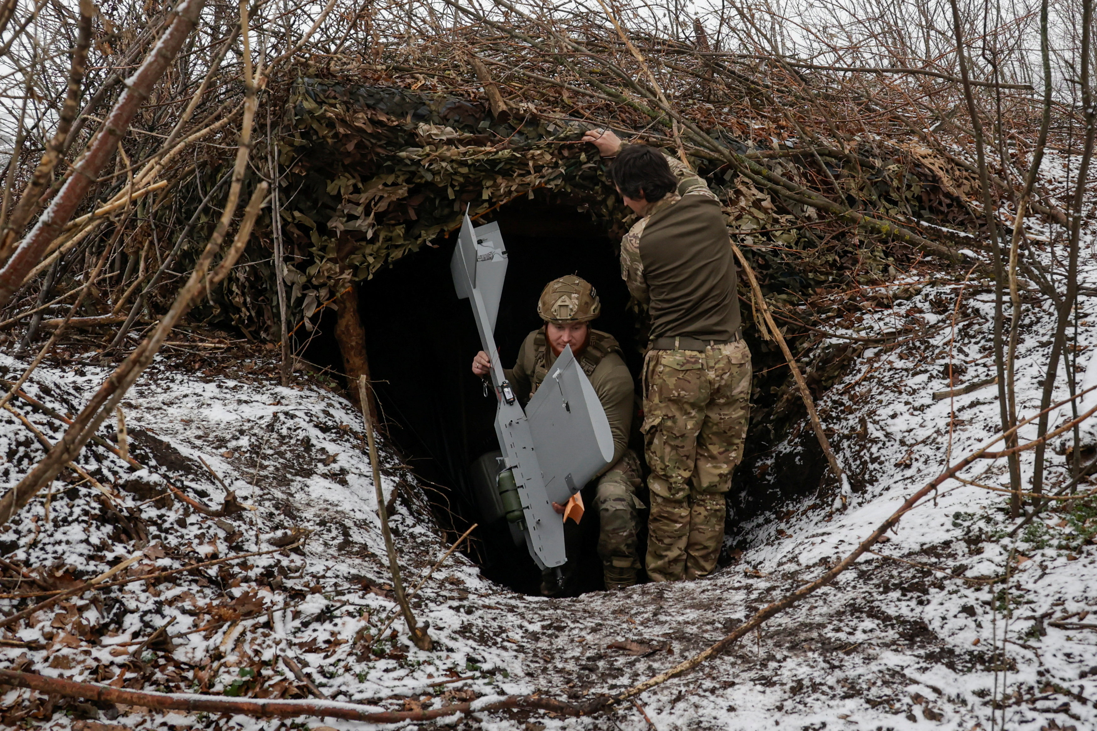 Servicemen of the 66th Separate Mechanized Brigade named after Prince Mstyslav the Brave leave their dugout with a Darts middle range strike unmanned aerial vehicle before launching it towards Russian troops from their position near a front line, amid Russia's attack on Ukraine, in Donetsk region, Ukraine, December 16, 2025. REUTERS/Sofiia Gatilova TPX IMAGES OF THE DAY