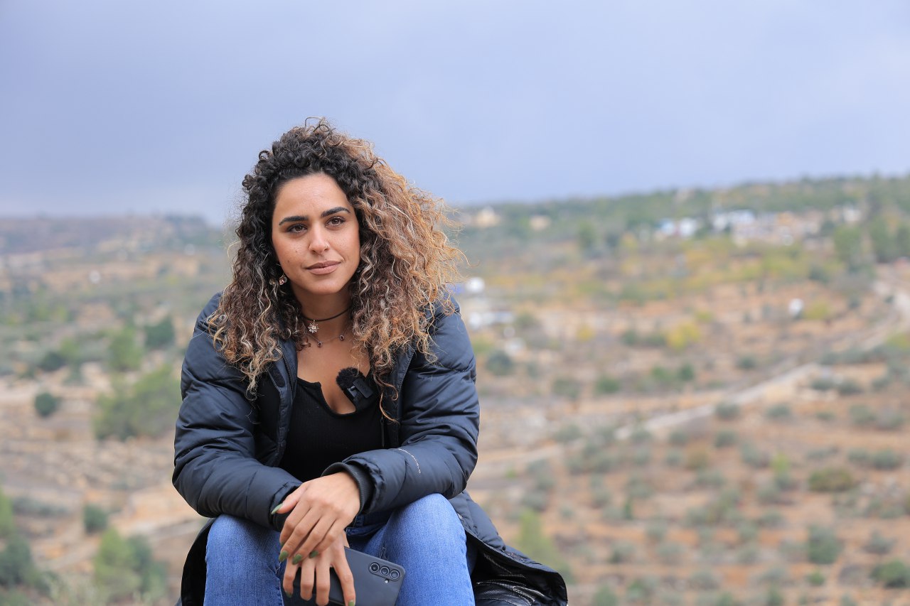 Alice Kisiya sits in front of her land