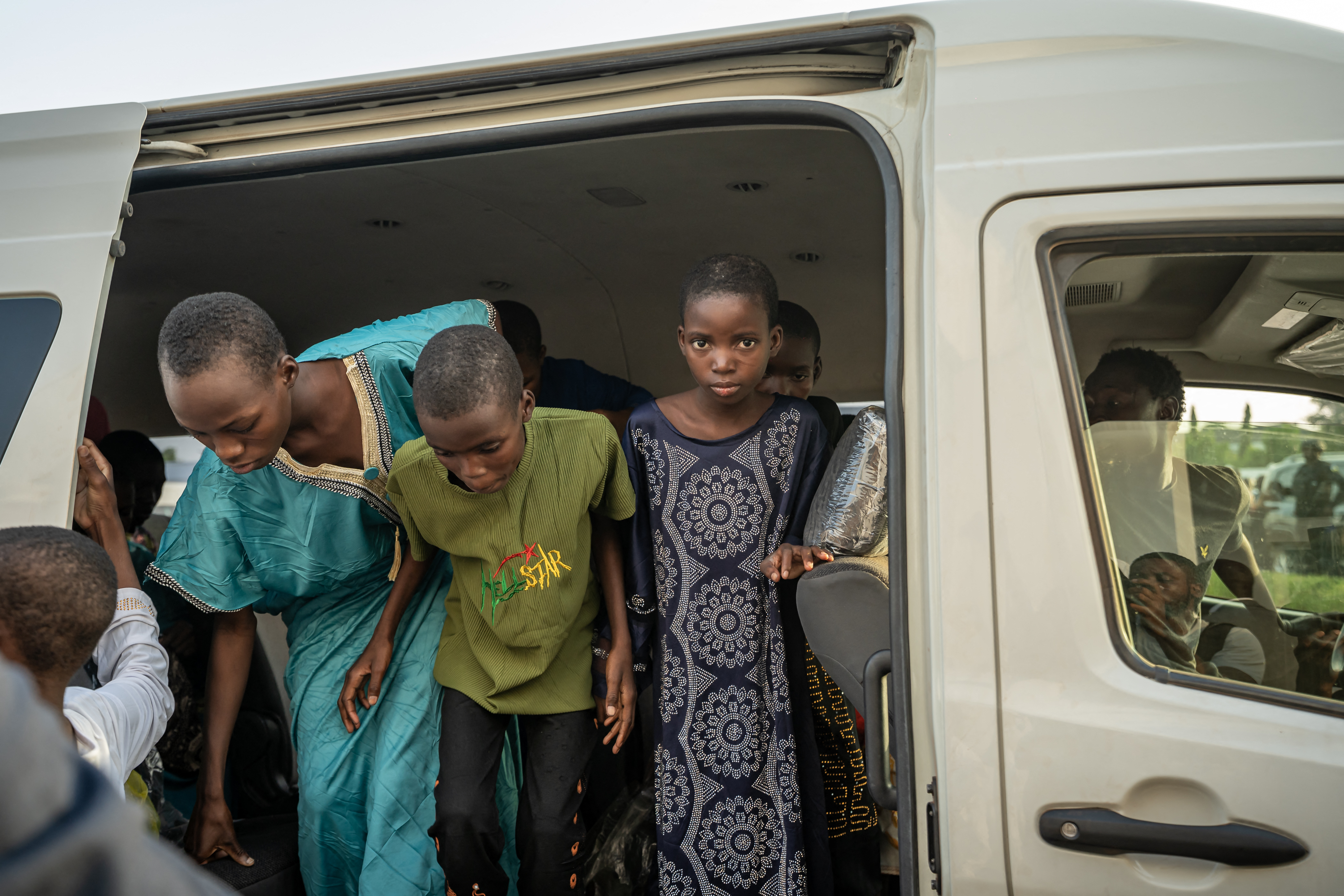 Schoolchildren leave a minibus as they arrive at the local Governor's office in Minna on December 8, 2025.
