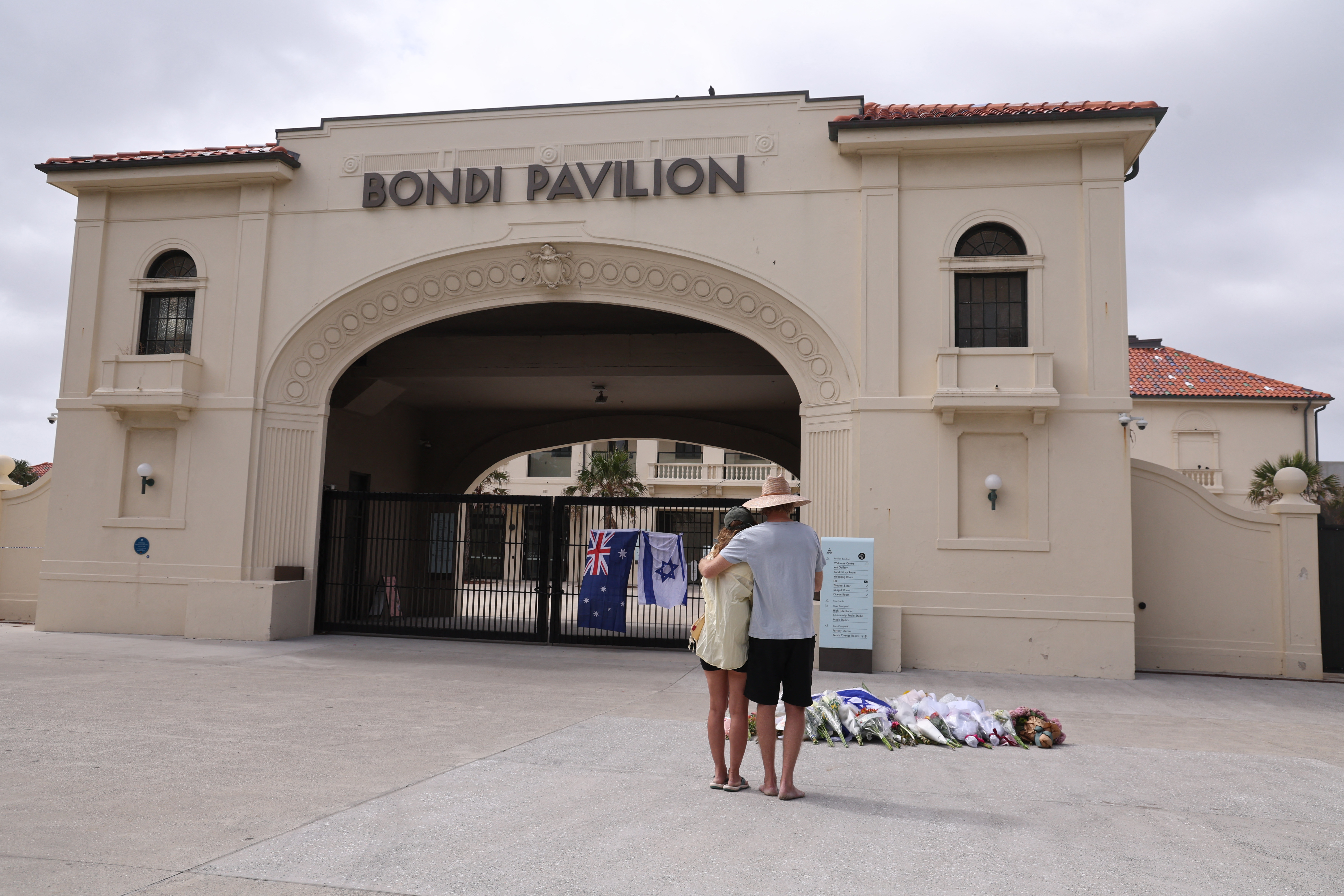 People look at flowers laid in memory of victims.