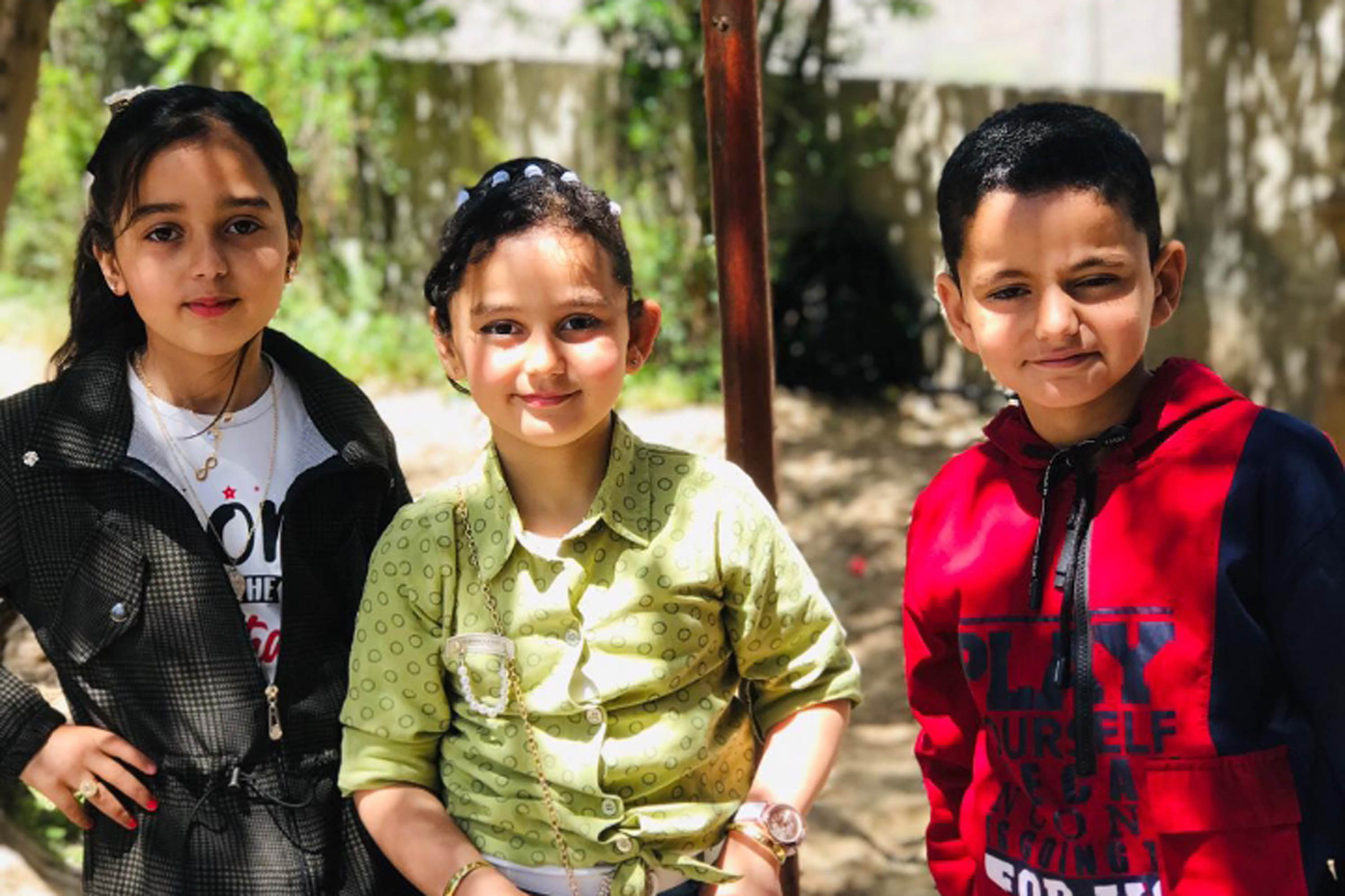 A photo of two girls and boy posing