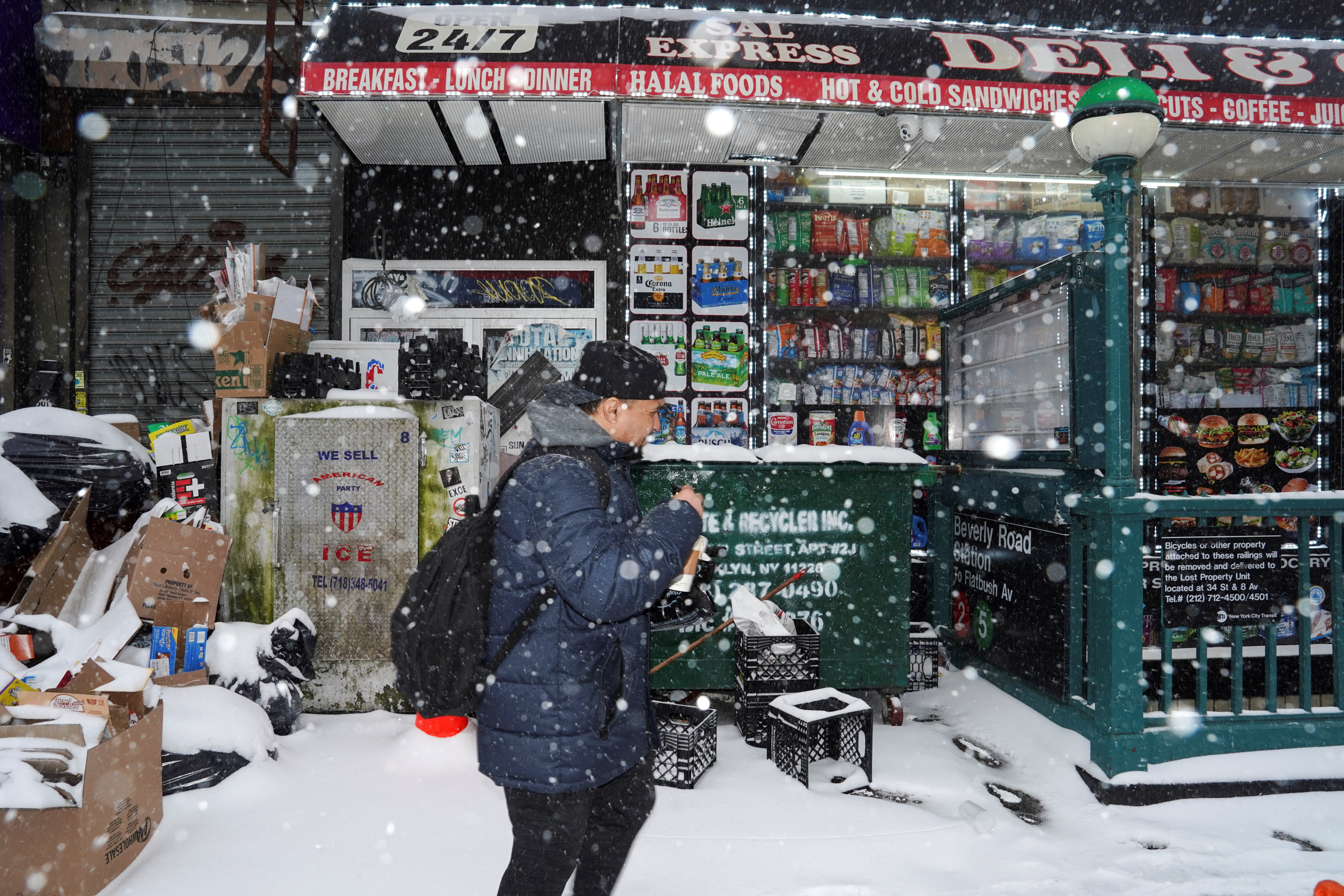 A person walks past a deli in snowy weather