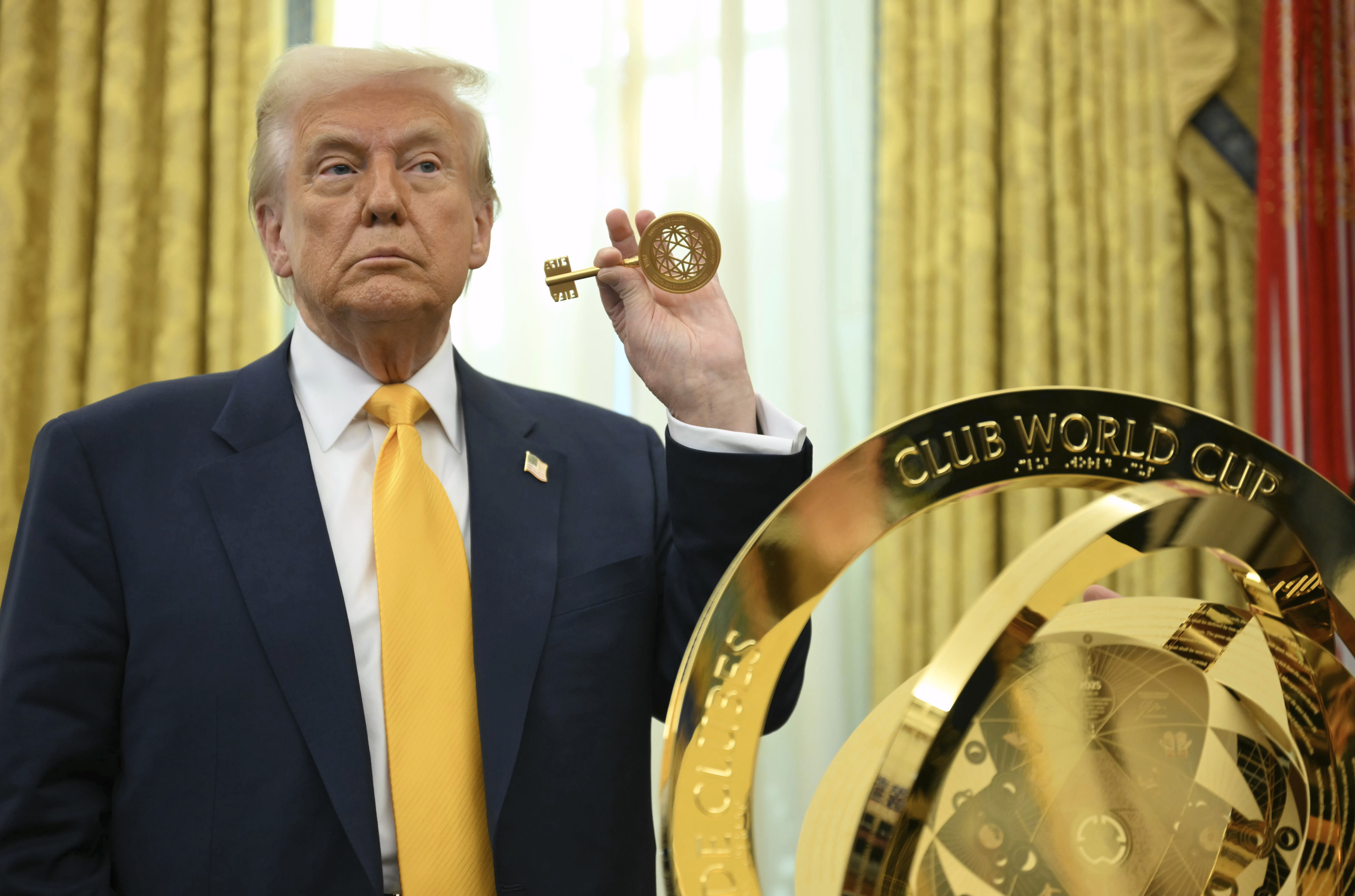Trump holds up a key in front of the FIFA Club Cup Trophy