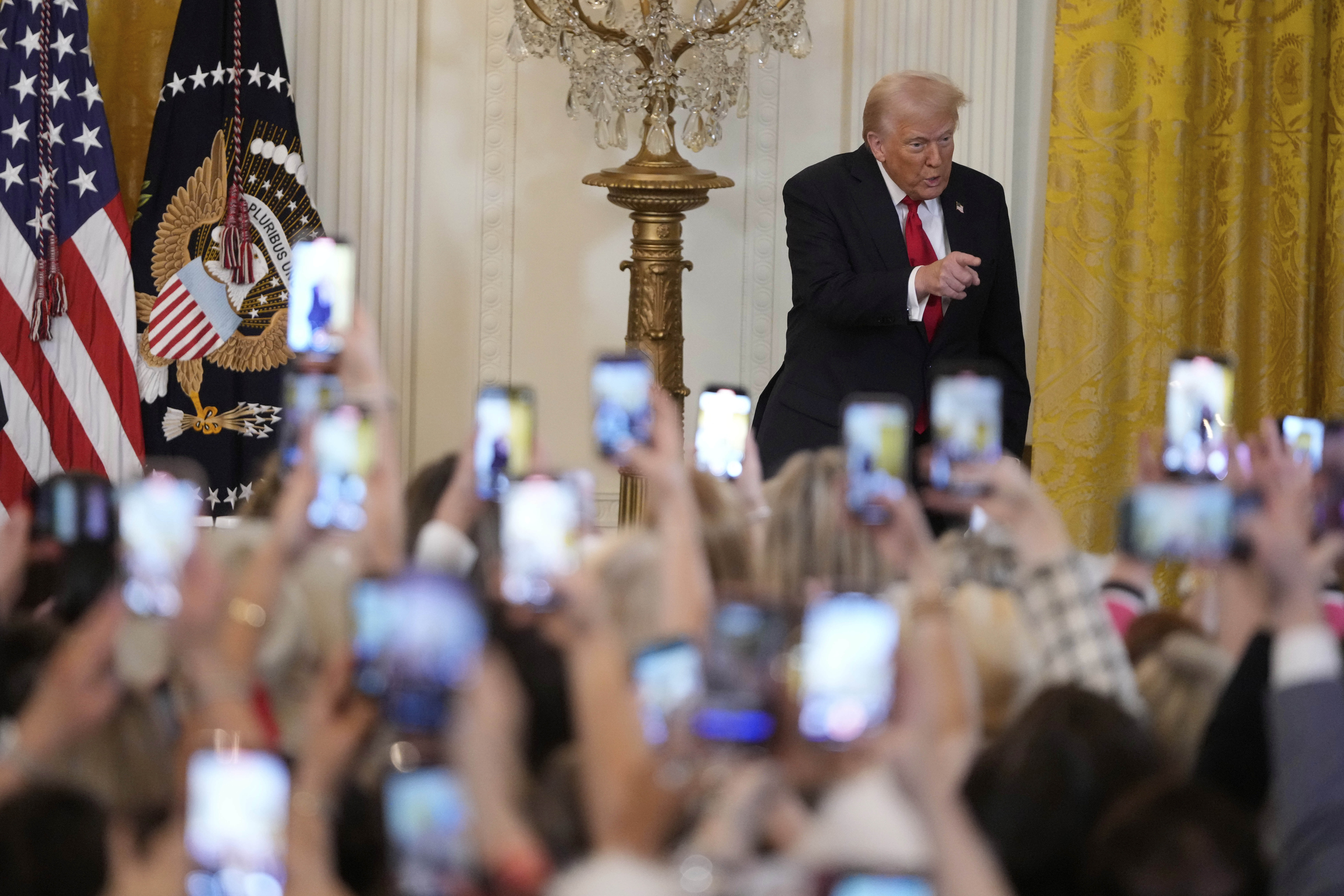 Audience members lift their cell phones to record Trump