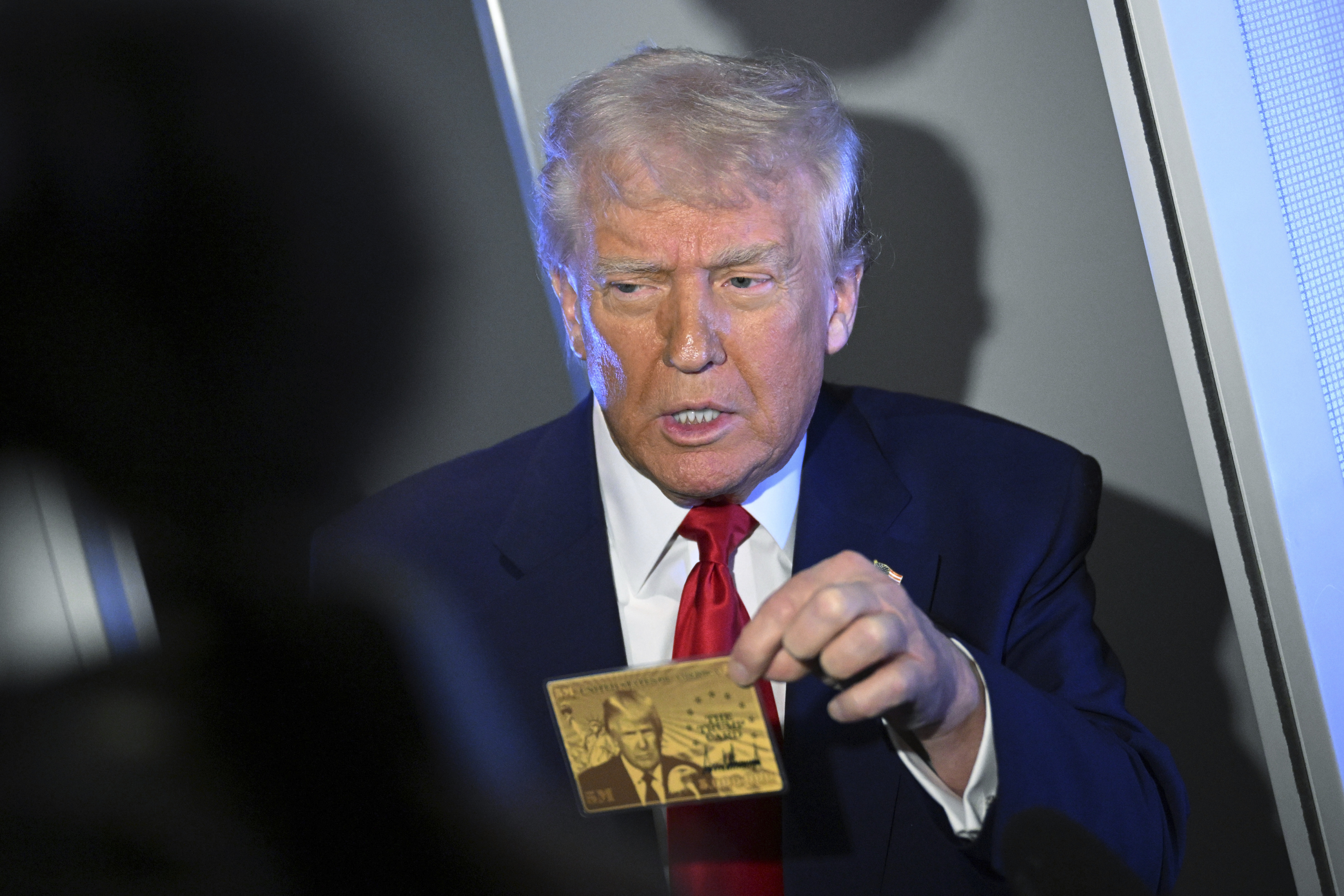 Donald Trump holds up his "gold card" in Air Force One.