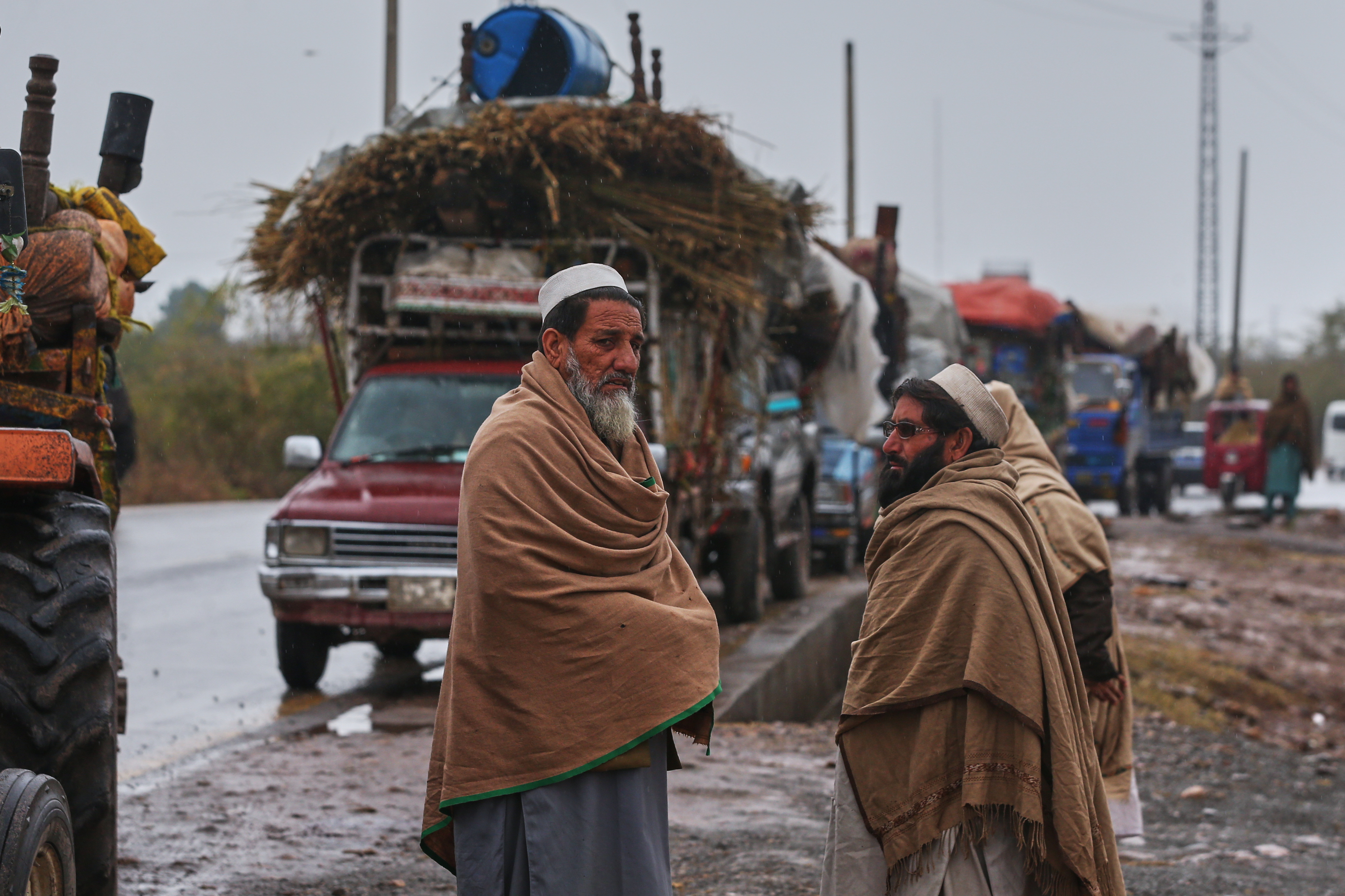 People stand near vehicles laden with belongings.