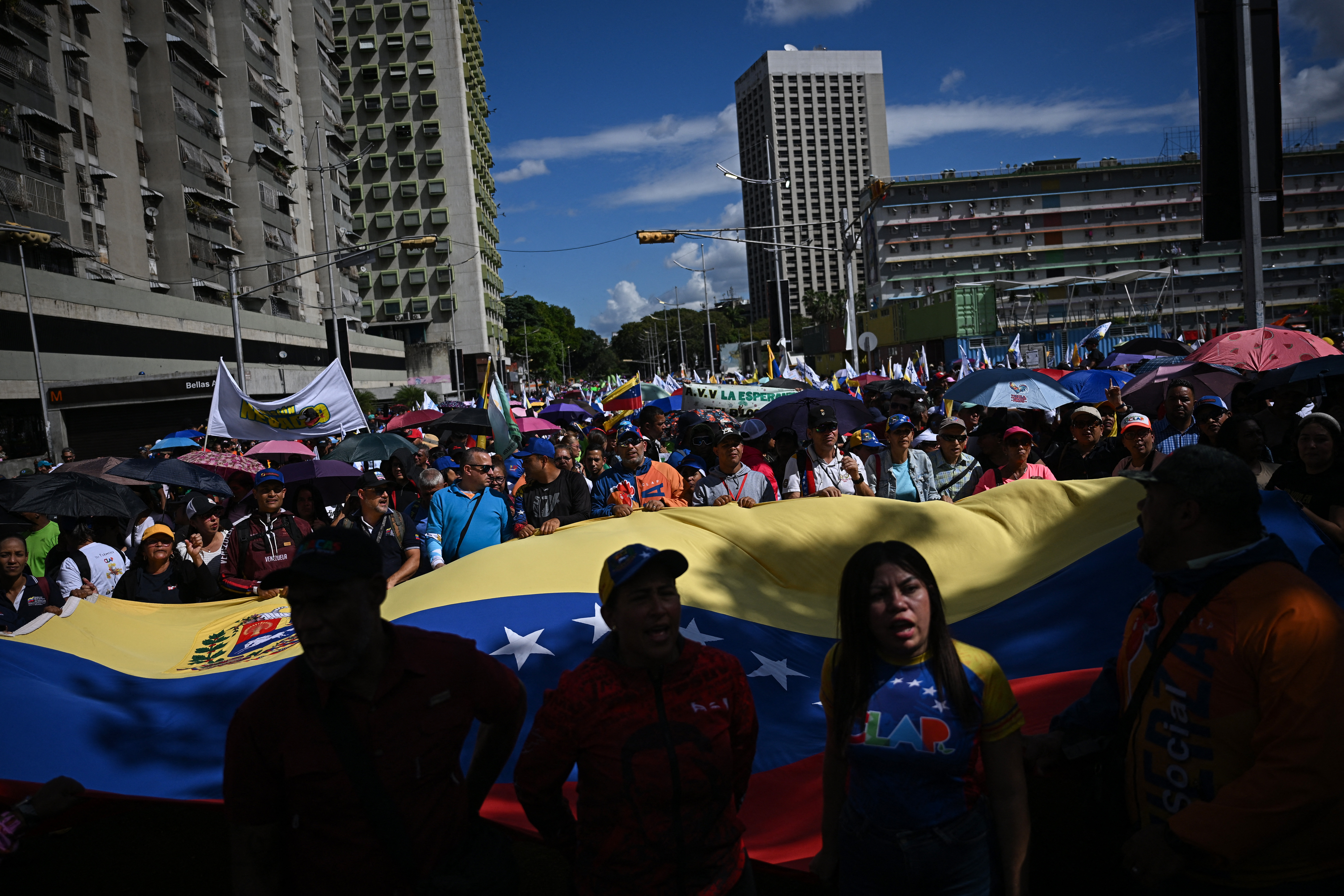 People hold a giant Venezuelan flag during a march in Caracas on January 9, 2026, to demand the release of deposed Venezuelan president Nicolas Maduro and his wife Cilia Flores, snatched and taken to New York on January 3 to face trial on drug and weapons charges.