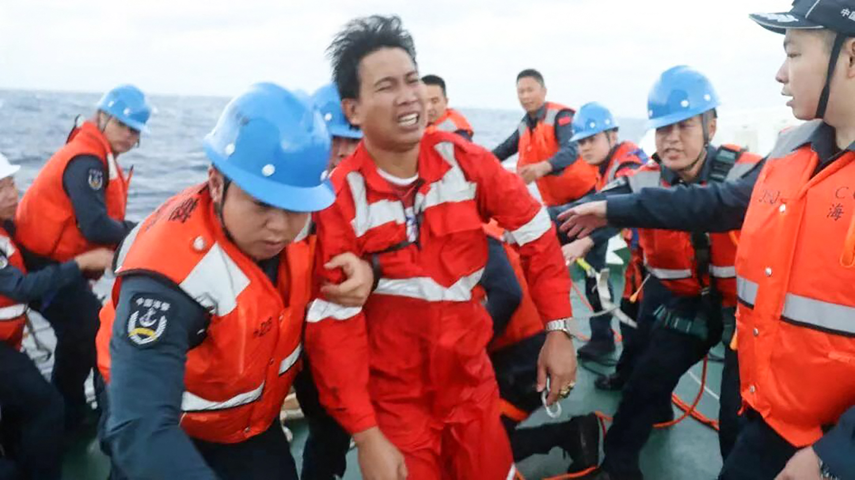 This handout from the Chinese Coast Guard taken and released by the Chinese embassy in Manila on January 23, 2026 shows Chinese Coast Guard personnel assisting a rescued Filipino crew member of a capsized cargo ship near the contested Scarborough Shoal in the South China Sea.
