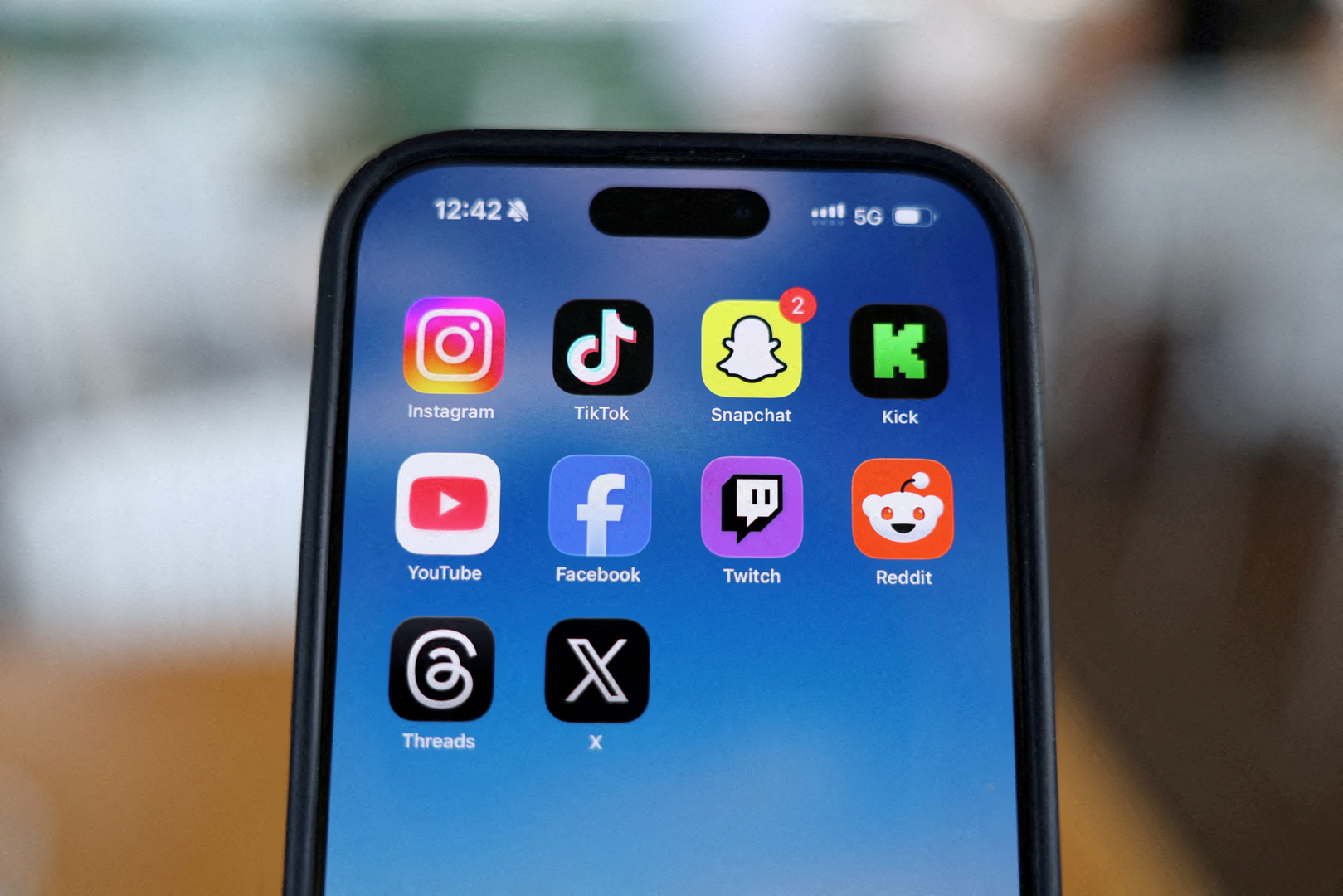 Instagram, TikTok, Snapchat, Kick, YouTube, Facebook, Twitch, Reddit, Threads and X applications are displayed on a mobile phone in this photo taken on Dec. 9, 2025. [File: Hollie Adams/Reuters]