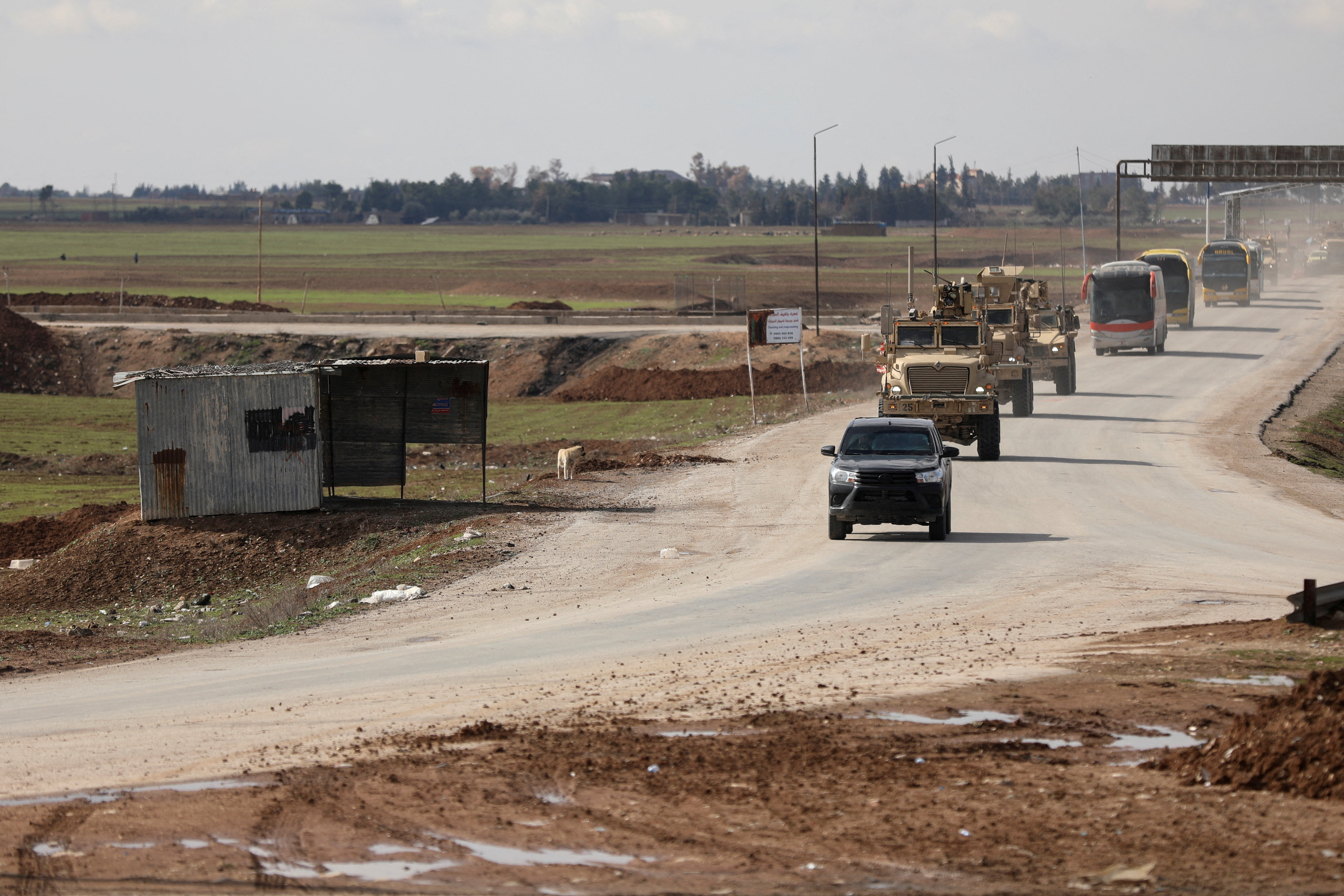 U.S. military vehicles move ahead of buses transporting Islamic State detainees from Syria to Iraq