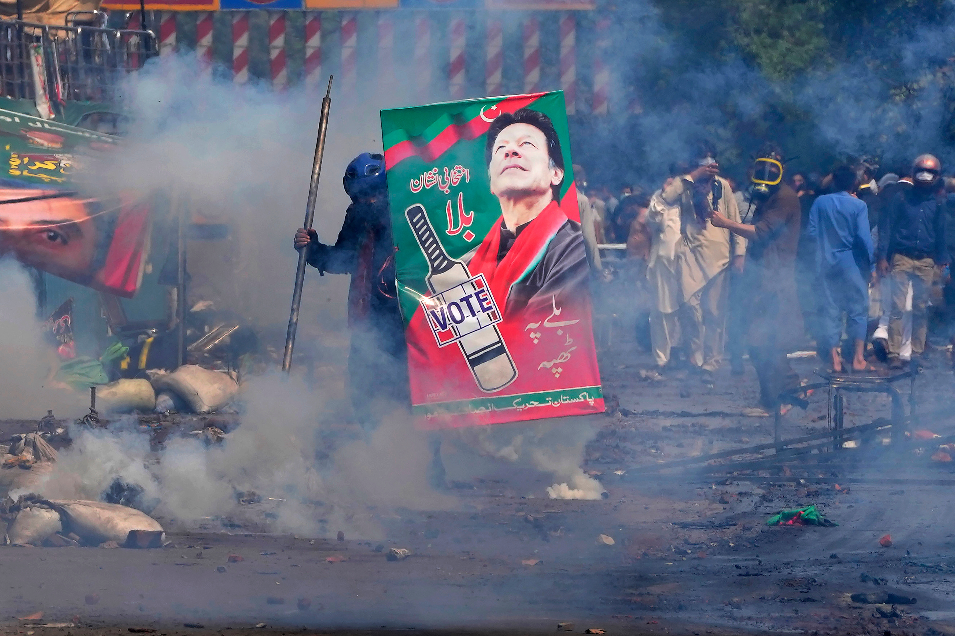 Supporters of former Prime Minister Imran Khan take cover after riot police officers fire tear gas to disperse them.