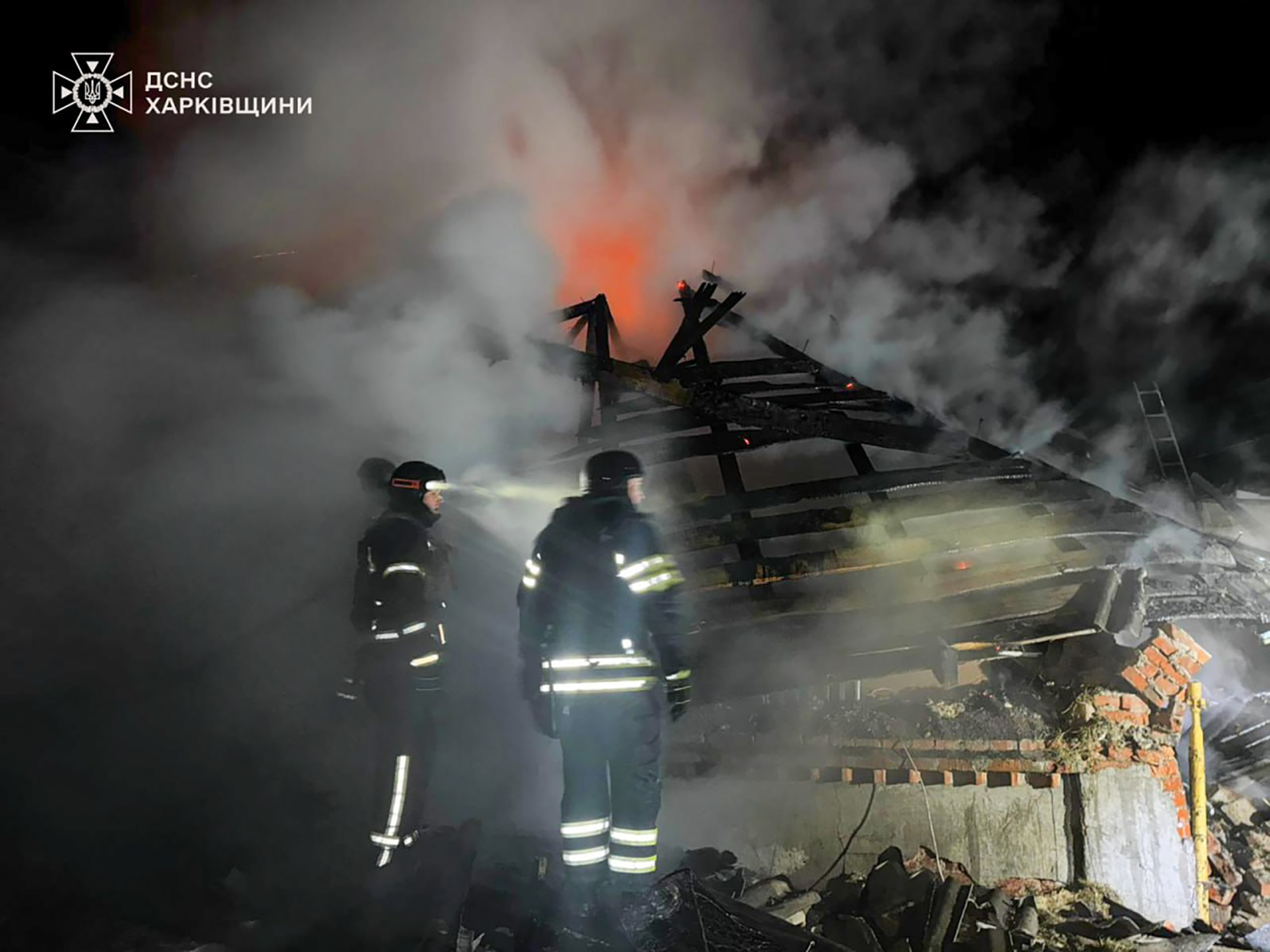 In this photo provided by the Ukrainian Emergency Service, emergency services personnel work to extinguish a fire at a private house following a Russian air attack in Bohodukhiv, Kharkiv