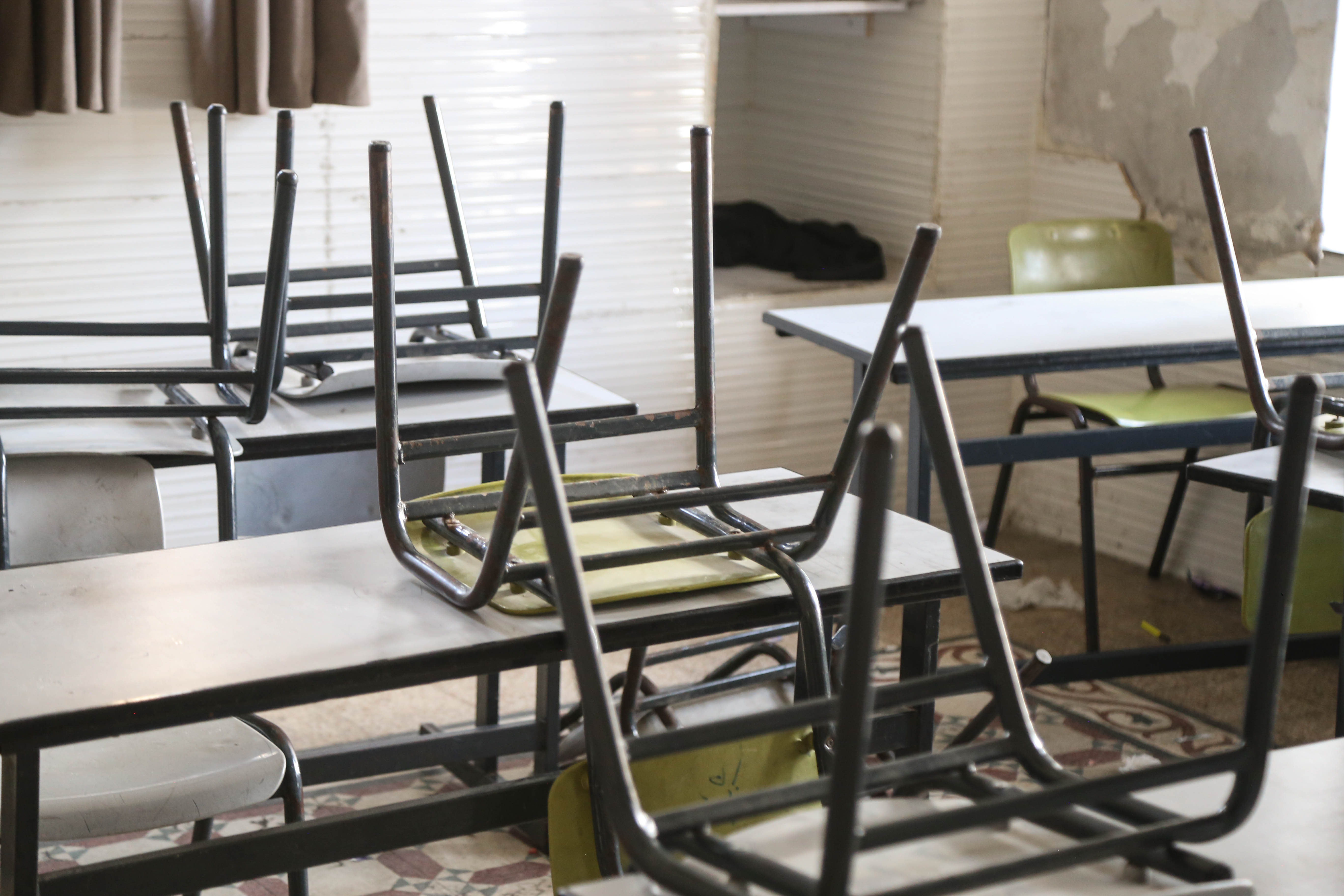 Chairs turned over desks in an empty classroom