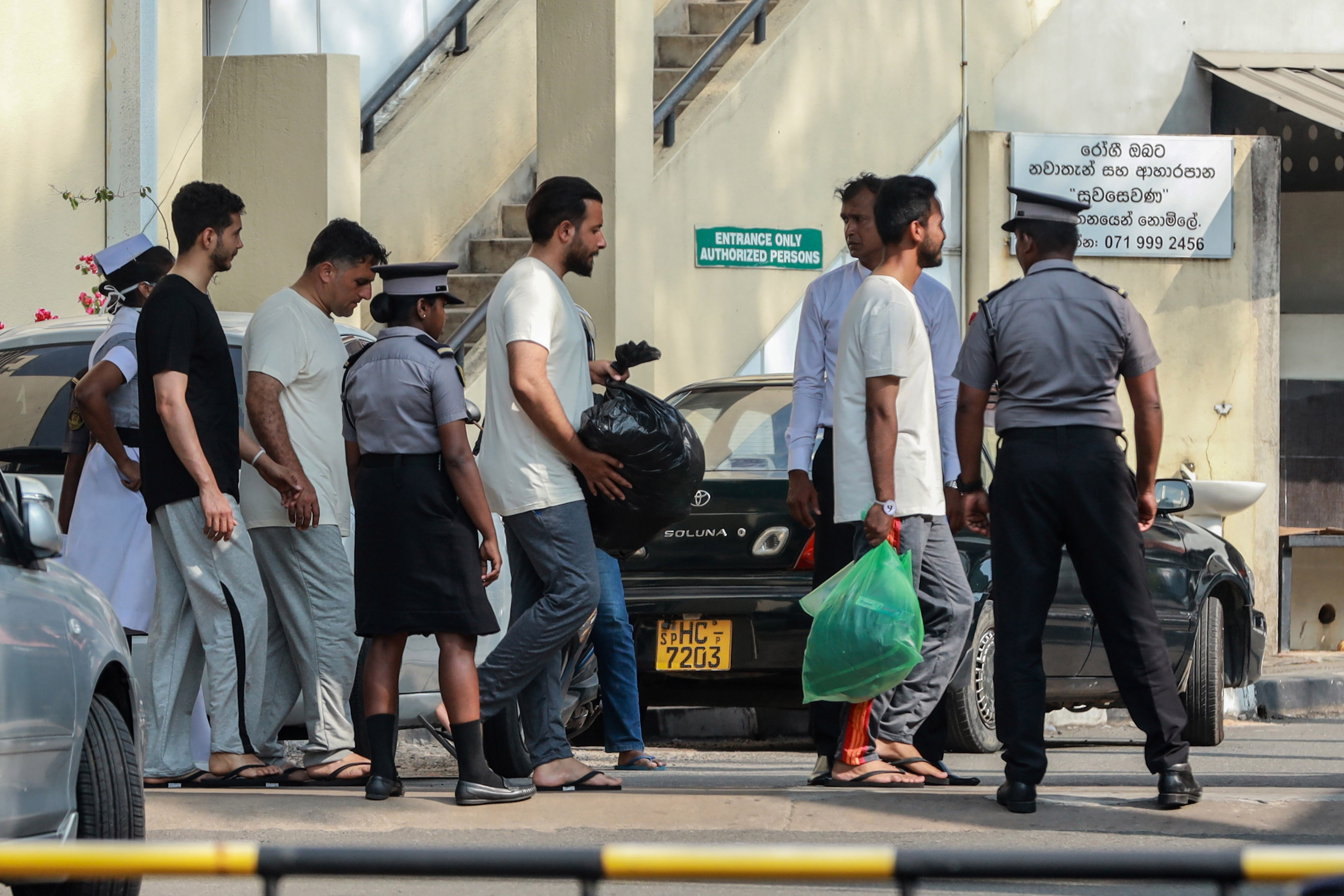Two Iranian sailors, center, who were rescued from IRIS Dena warship by Sri Lanka's navy are escorted to a Judicial Medical Officer