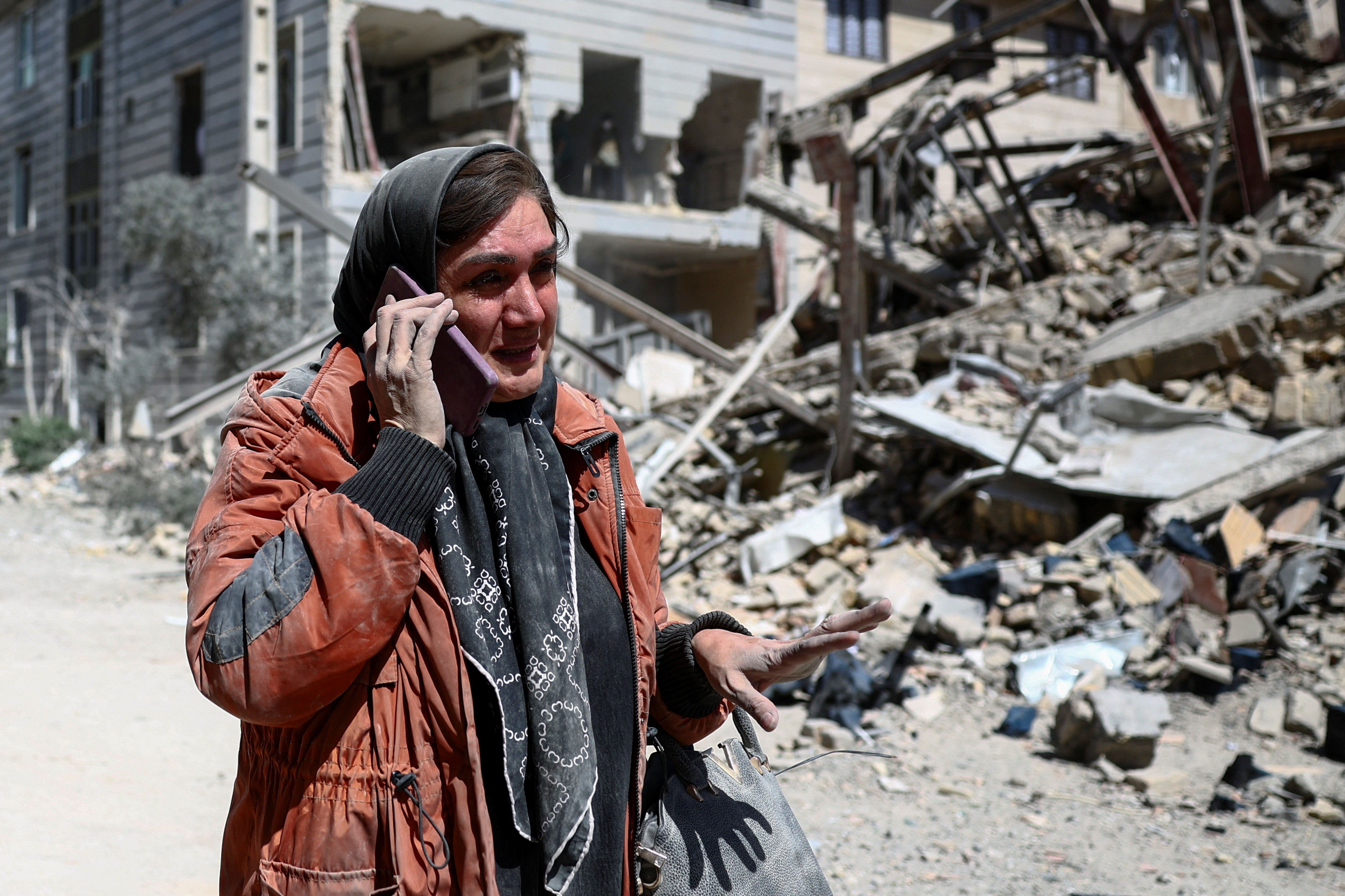 A woman amid a damaged residential neighbourhood in Tehran