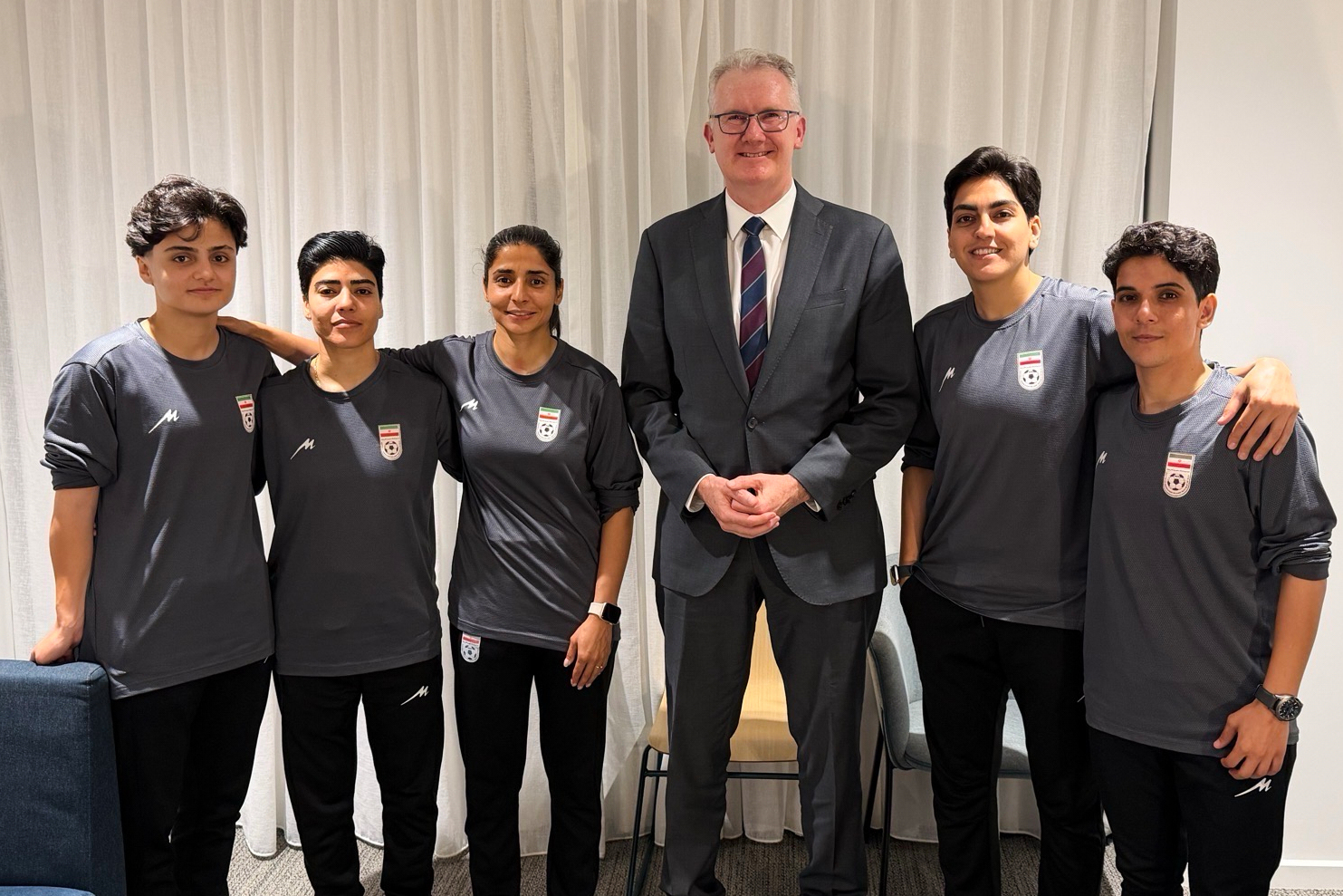 Australian Immigration Minister Tony Burke, centre, poses in an undisclosed location with five Iranian women football players.