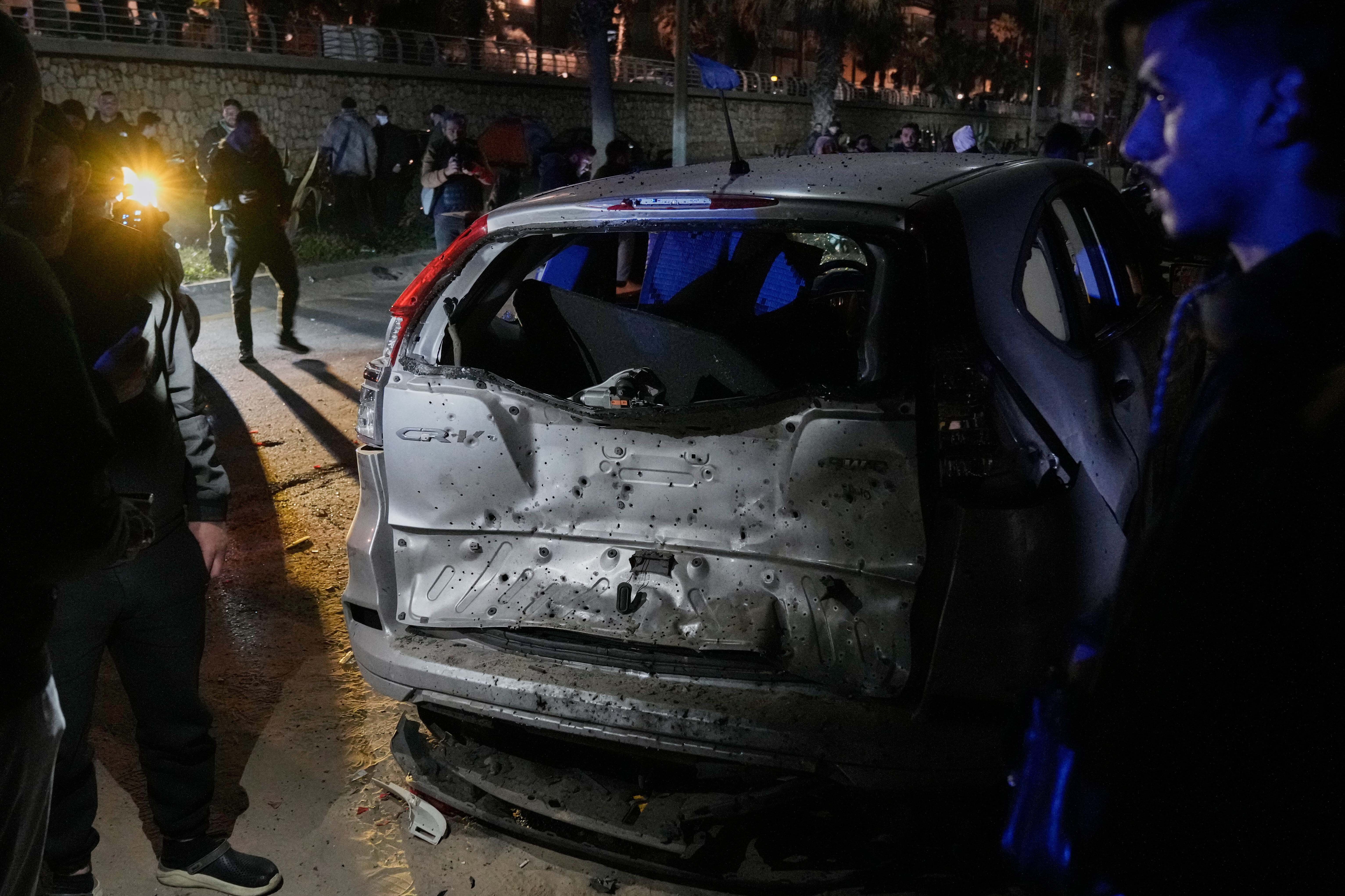 People gather near a damaged car hit in an Israeli airstrike at the Ramlet al-Baida public beach, in Beirut, Lebanon, early Thursday, March 12, 2026. [Bilal Hussein/AP Photo]