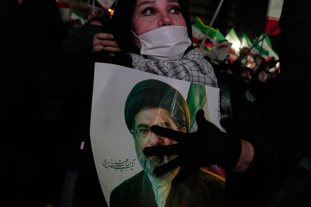 A woman holds a picture of the Iranian Supreme Leader Ayatollah Mojtaba Khamenei