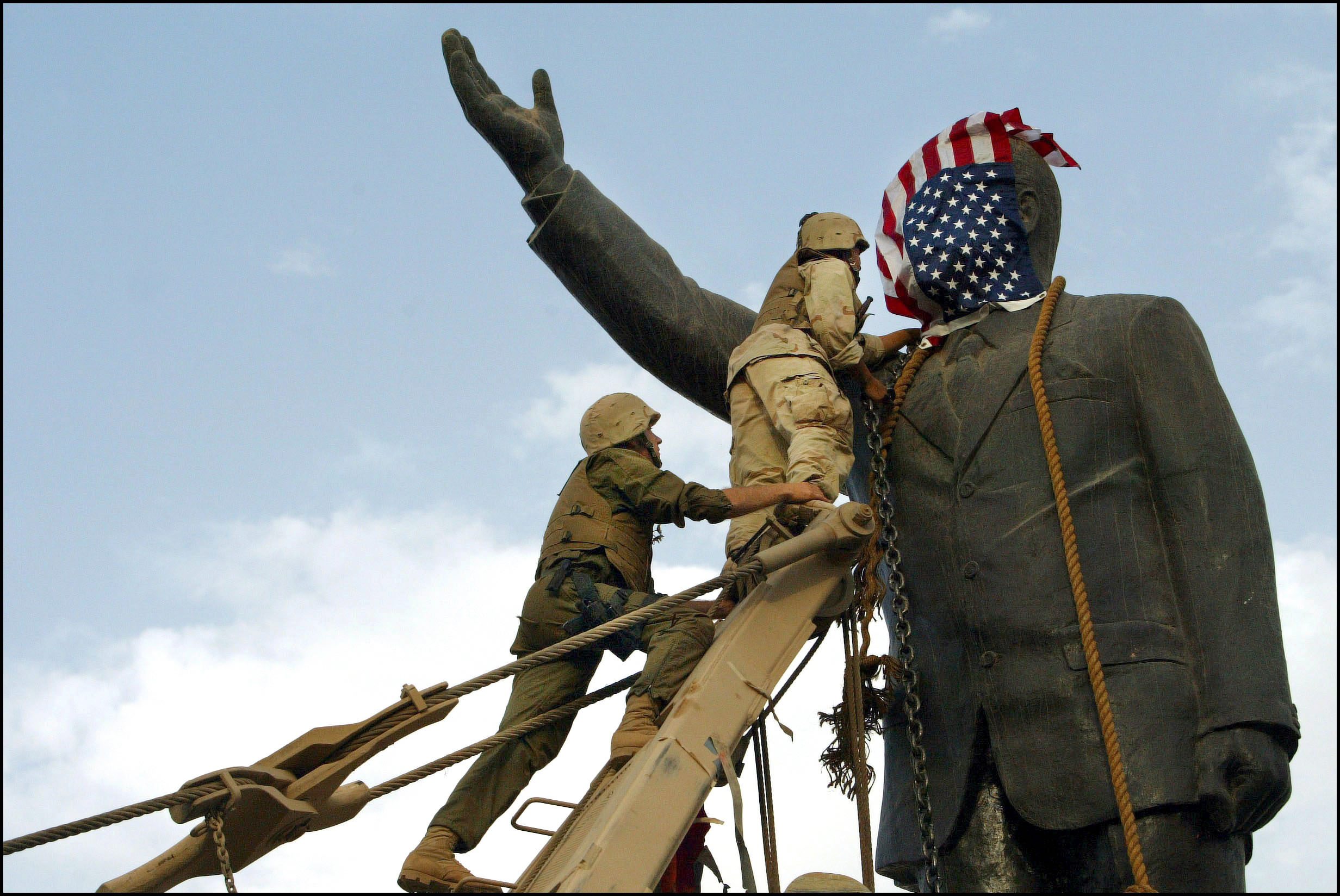  IRAQ - APRIL 09: Operation Iraqi Freedom - Day 21: Us Troops Enter Central Baghdad And Topple Statue Of Saddam Hussein On April 9, 2003 In Baghdad, Iraq. Members Of The Us Marine 3Rd Battalion 4Th Regiment Share In The Celebration With Iraqis. Liberated By U.S. Led Troops, Thousands Of Jubilant Iraqis Celebrated The Collapse Of Saddam Hussein Murderous Regime, Beheading A Toppled Statue Of Their Longtime Ruler In The Center Of Baghdad And Looting Government Sites. (Photo by Gilles BASSIGNAC/Gamma-Rapho via Getty Images)